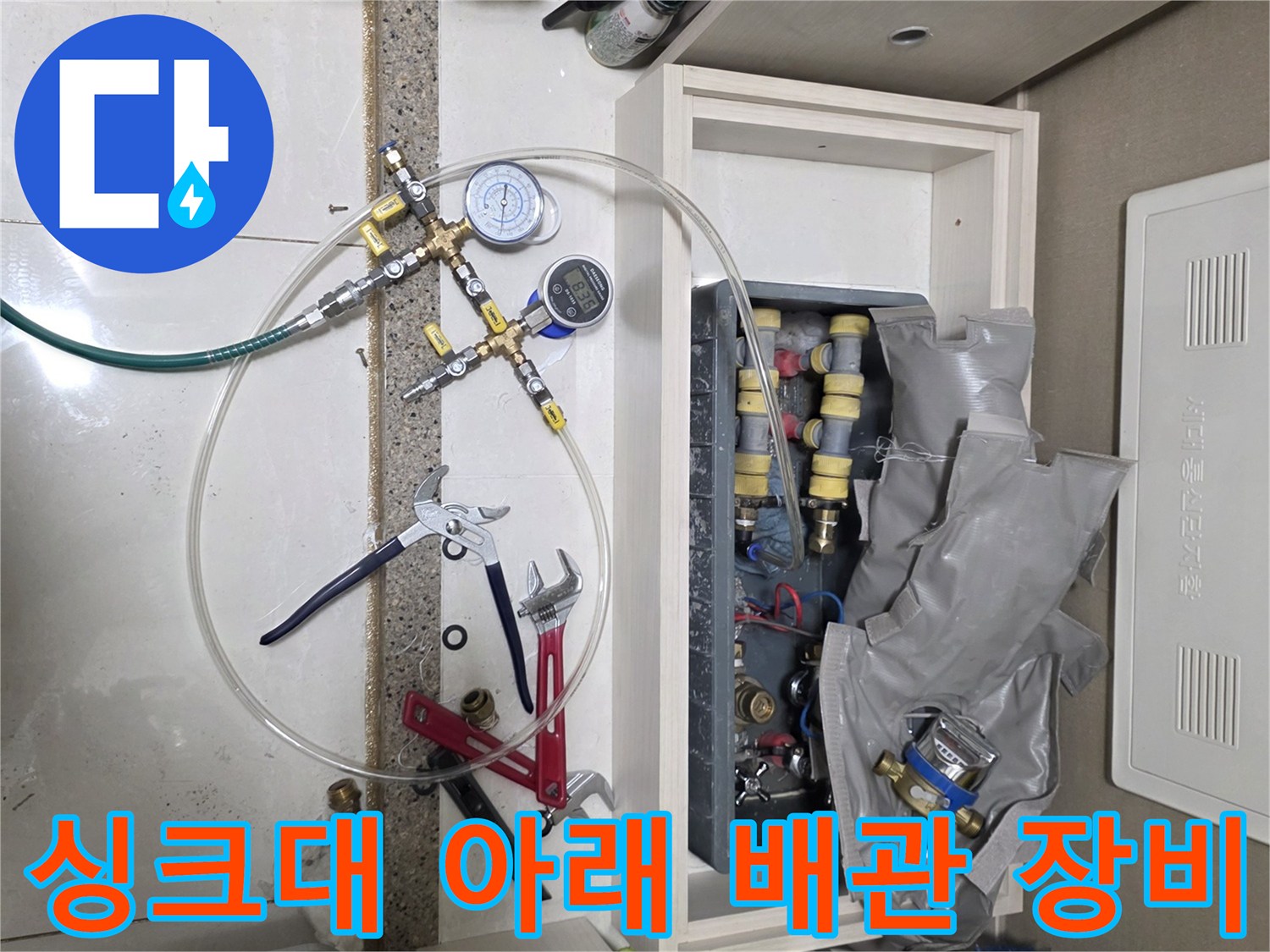 누수 지점을 찾기 위해 싱크대 하부 공간에 설치된 압력 측정 장치와 밸브