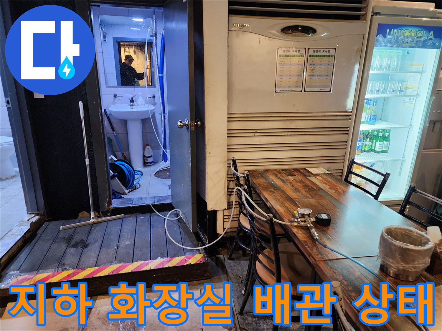 지하 화장실 내부의 노출된 파란색 주름관과 복잡한 배관 연결 부위 모습