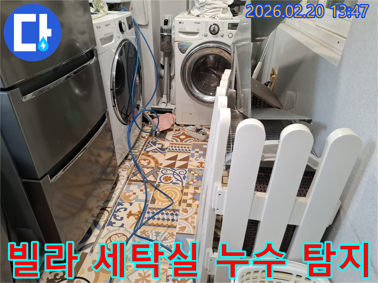 빌라 세탁실 바닥에 누수 탐지용 호스가 설치되어 있고-세탁기 옆으로 청소 도구가 보이는 현장입니다.