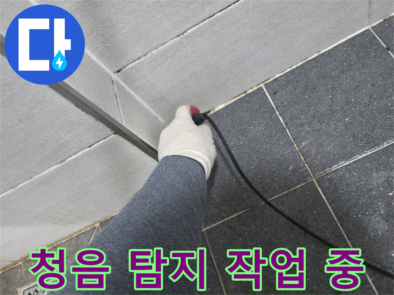 타일 경계 틈새에-탐지 센서를 대고-배관 상태를 확인하는 모습
