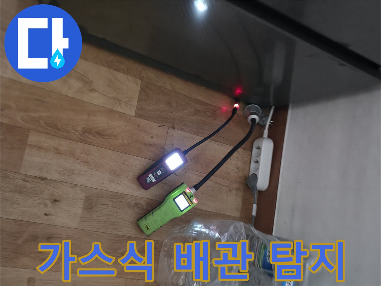 싱크대 아래 배관의 누수 지점을 찾기 위해 가스 탐지기를 사용하는 장면