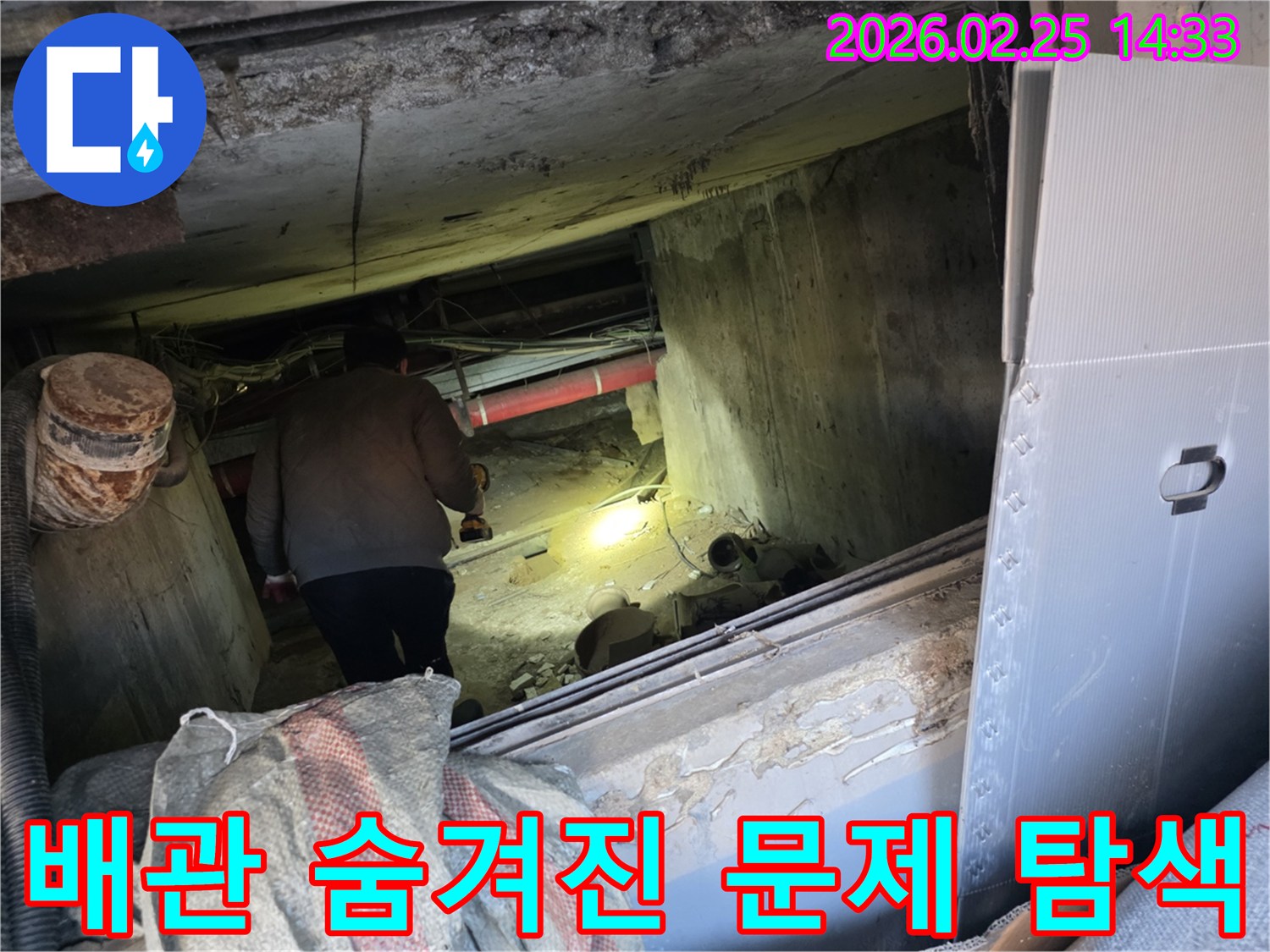 누수 전문 엔지니어가-어둡고 복잡한 배관이 얽힌 공간에서-손전등으로 구석구석을 비추며-배관의 숨겨진 문제점을-정밀하게 탐색하는 전문적인 모습입니다.