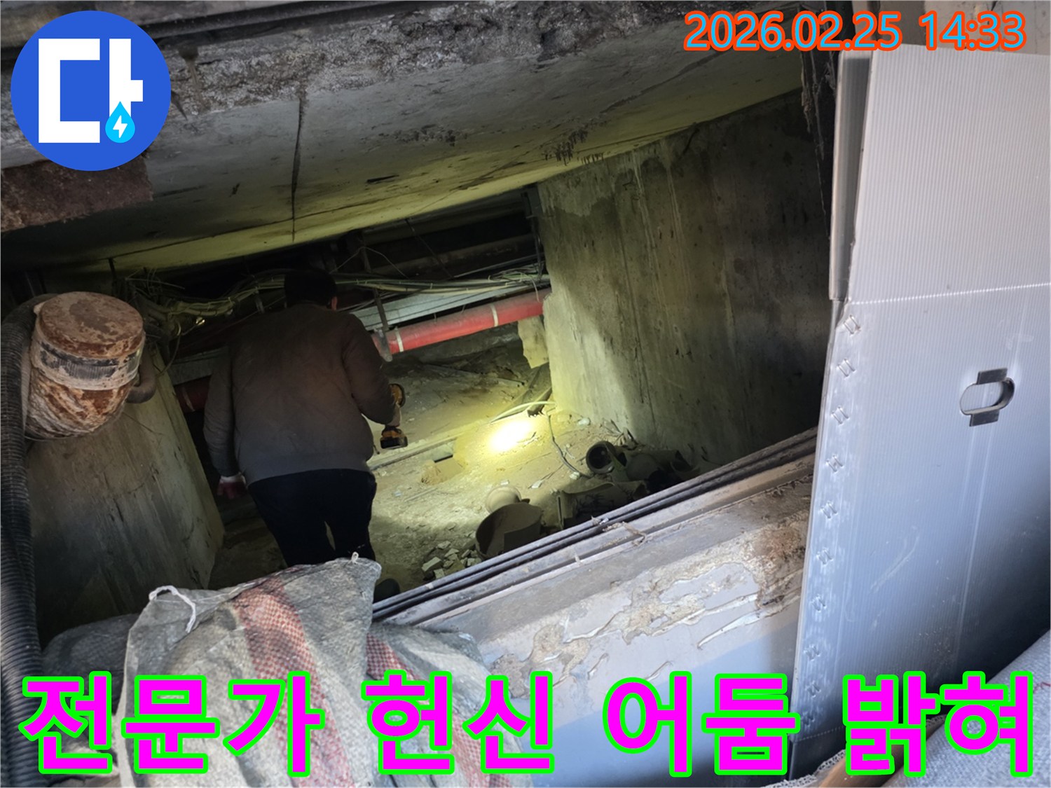 누수 전문 엔지니어가-어둡고 좁은 공간에서-손전등을 비춰가며-고객의 불편을 해소하기 위해-헌신적으로 누수 지점을-탐지하는 모습입니다.