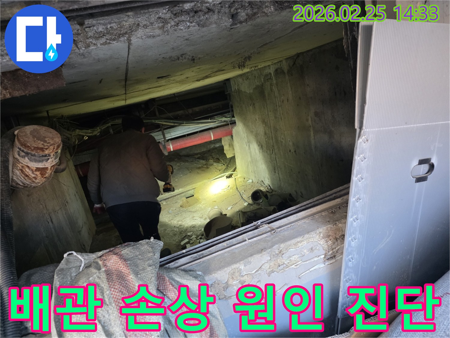 누수 전문 엔지니어가-어둡고 좁은 공간에서-손전등을 비춰가며-배관의 손상 여부를-정밀하게 진단하는 모습입니다.