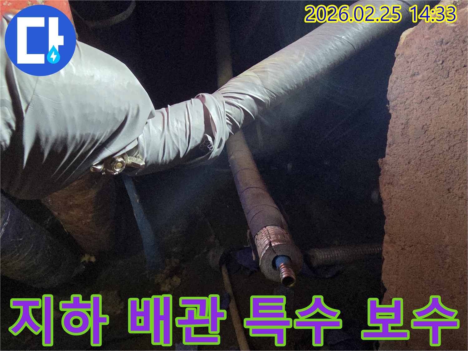 어둡고 좁은 지하 공간에서-장갑을 낀 손이-손상된 배관을-세심하게 점검하고-특수 보수 작업을-진행하는 전문가의-모습입니다
