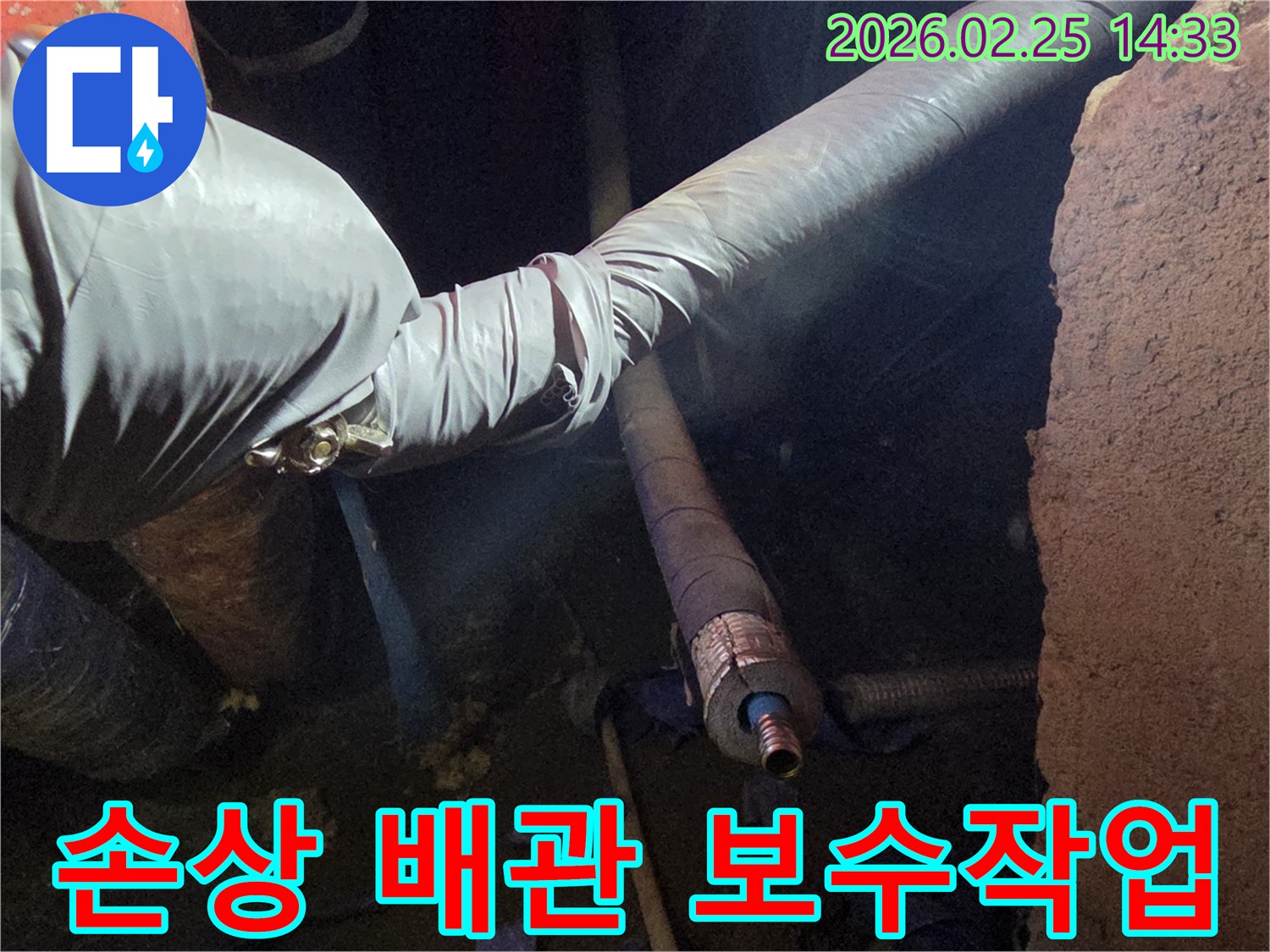 장갑을 낀 손이-어두운 곳에서-오래된 배관의-손상된 부분을-주의 깊게-점검하며-수리 준비를 하는-장면입니다
