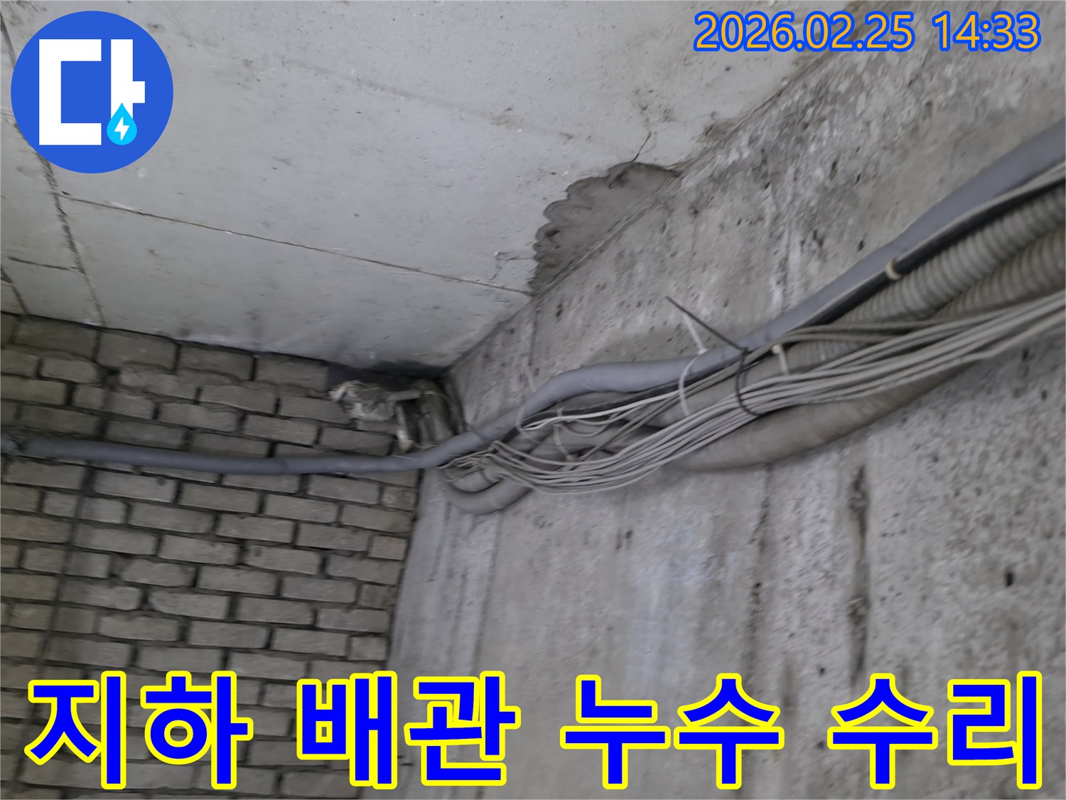 지하 벽면의-콘크리트와-벽돌 벽이 만나는-지점에서-발견된-오랜 누수로 인한-짙은 물자국과-주변 배관-그리고-수리 준비 흔적