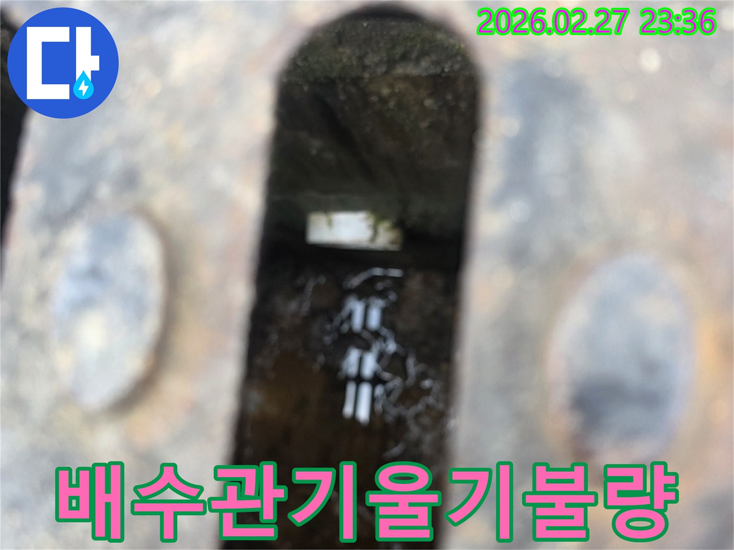 녹슨-철제-배수구-아래-고인-물과-물속에-잠긴-배관-일부가-보이는-배수관-기울기-불량-현장