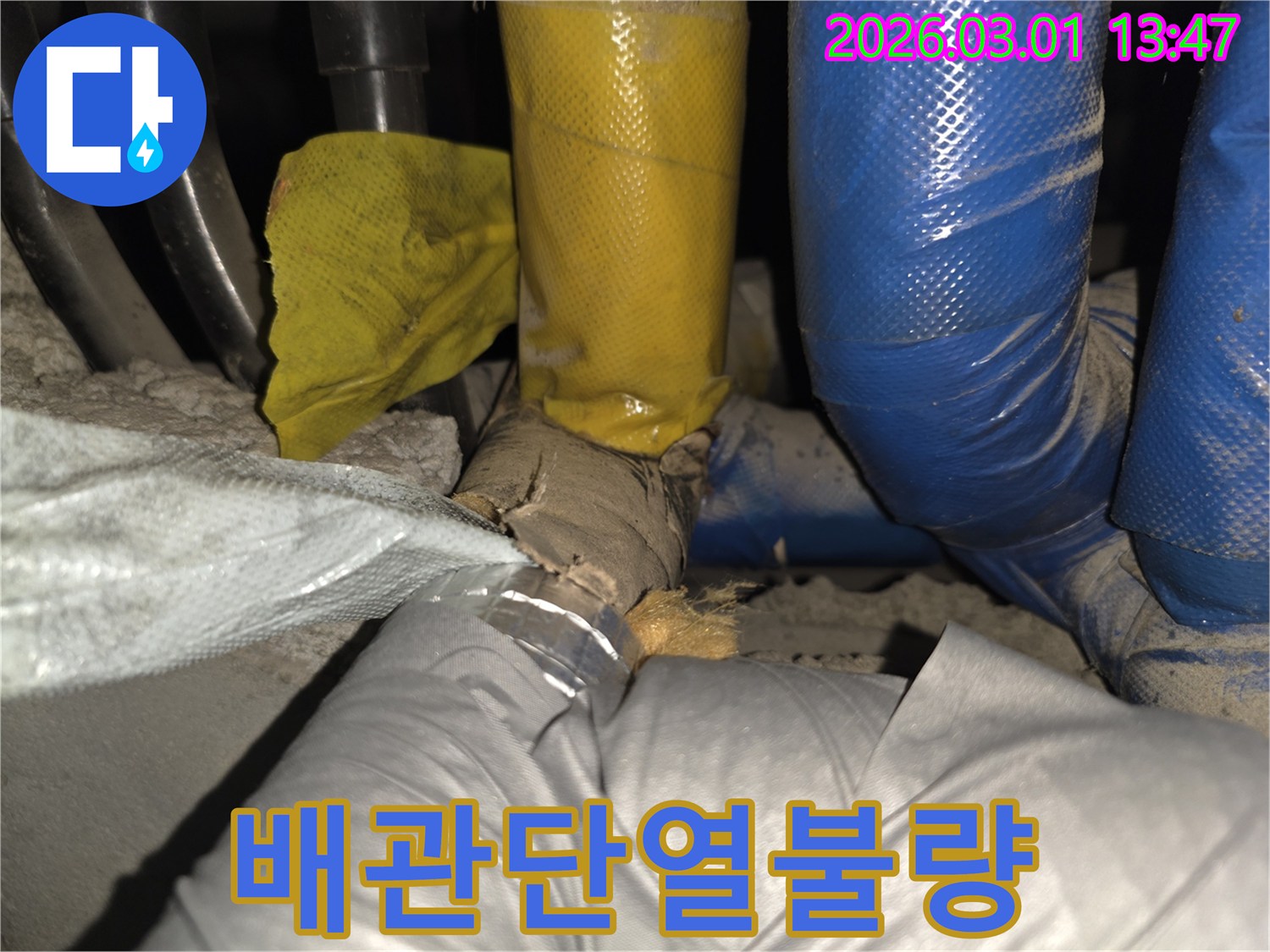 이 사진은 배관의 외부 마감재가 찢어져-내부 보온재가 드러난 모습을 보여줍니다.