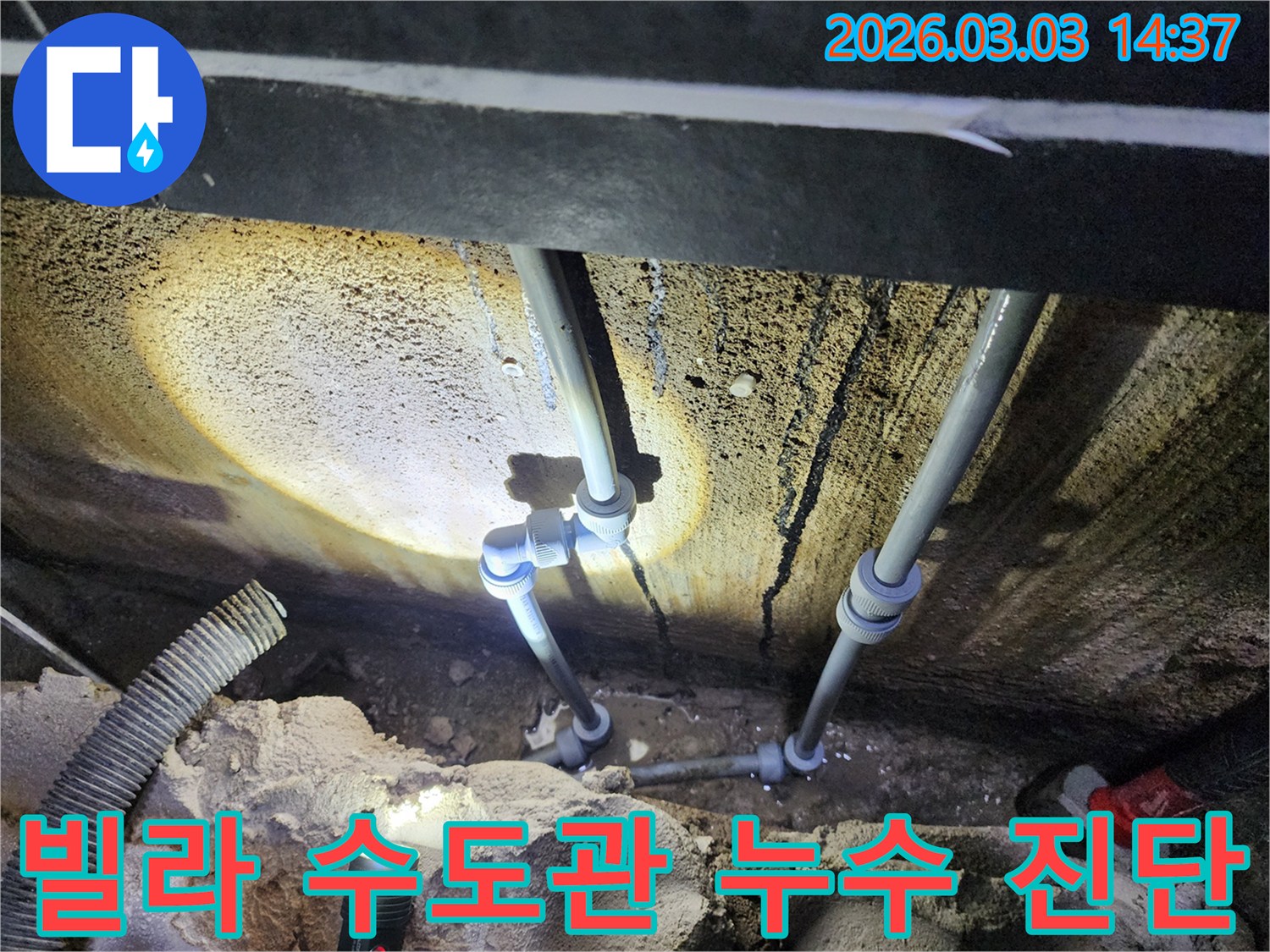 어두운 빌라 지하에서-손전등으로 비춘-수도 배관의-연결부 누수 지점을-전문가가 확인하는 모습입니다.