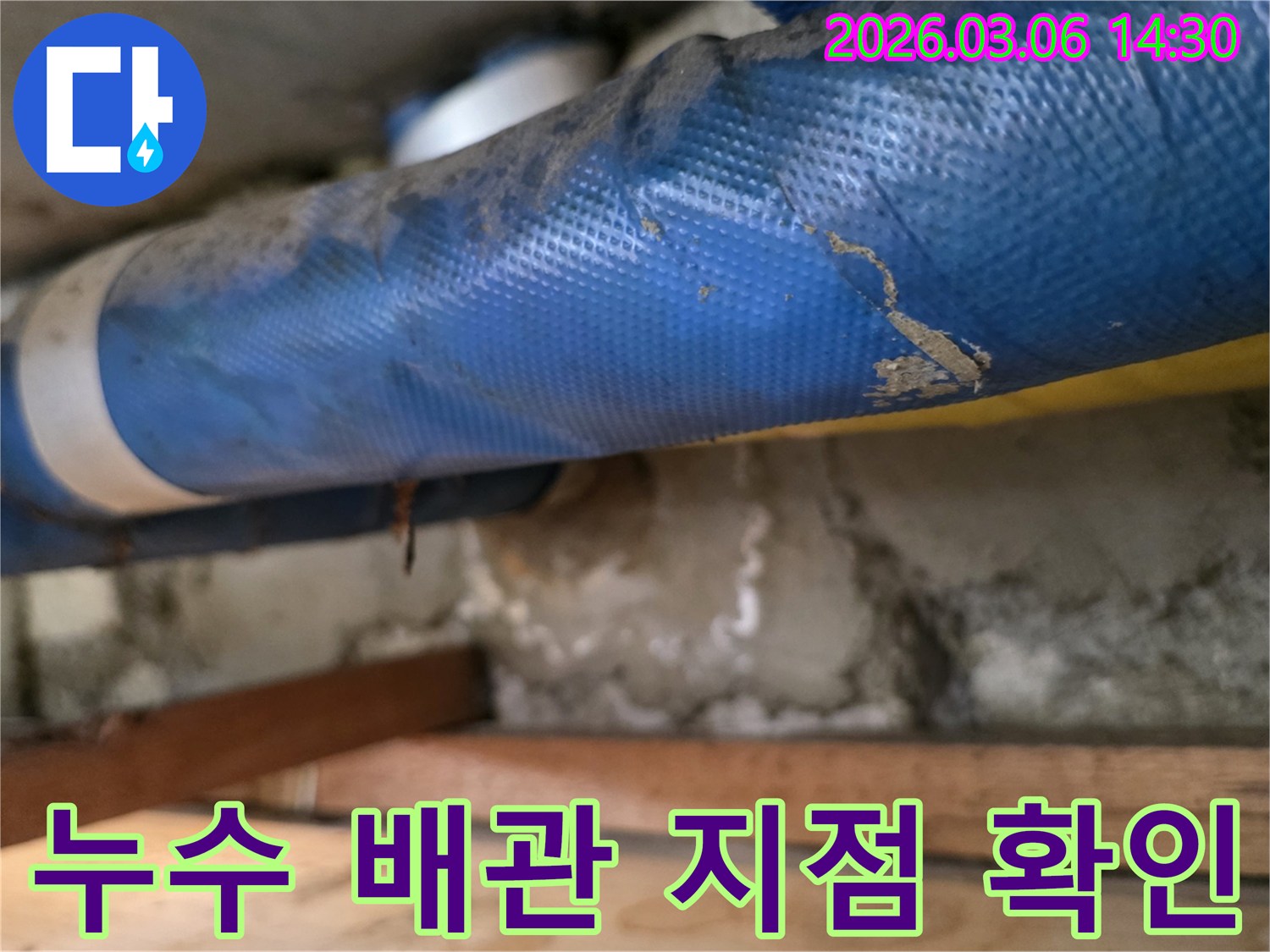 지하 공간에서-파란색 배관 주변의-젖은 콘크리트와-나무 구조물을-정밀하게 검사하는 모습