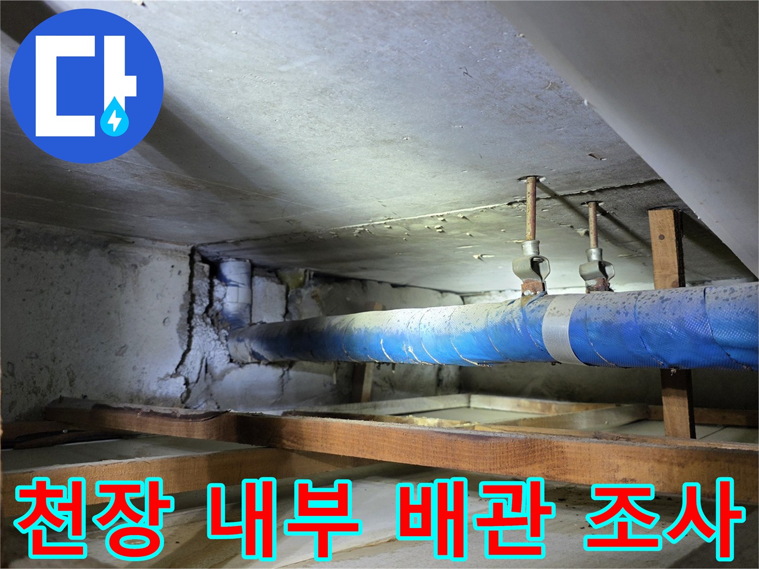 천장 틈새로 보이는-파란색 보온재가 감긴 배관과 고정 장치