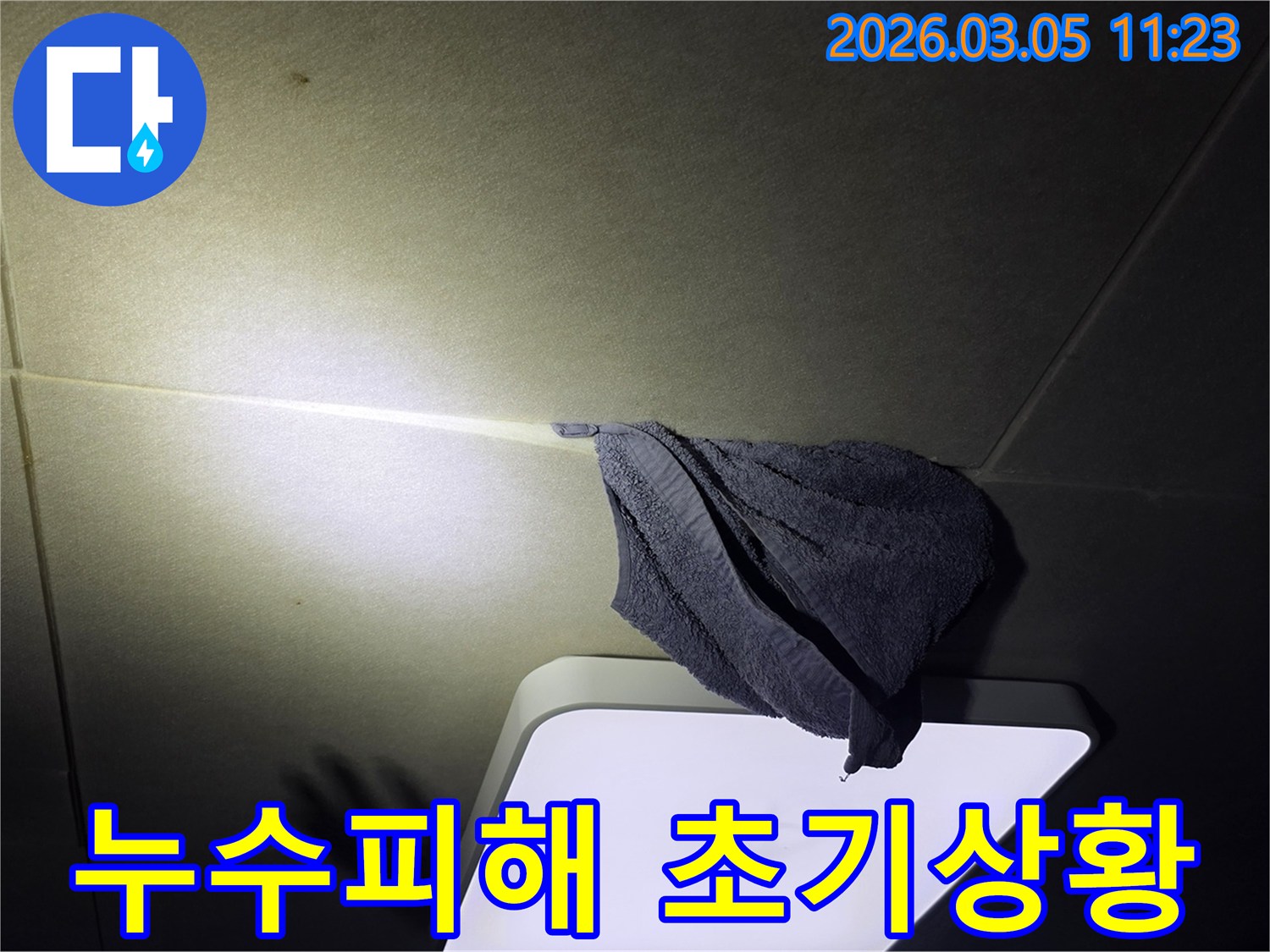 누수로-인해-천장-등기구-주변에-물이-떨어져-수건으로-임시-조치한-모습을-담은-사진
