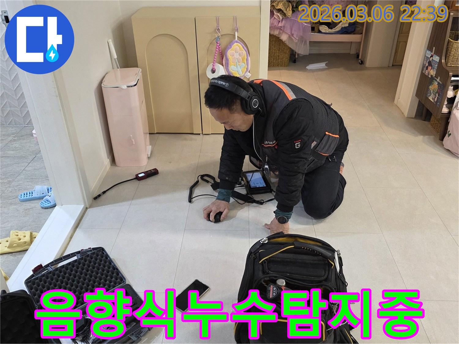 누수-전문가가-고성능-헤드폰과-탐지기를-활용하여-바닥-아래-숨겨진-누수-음을-집중적으로-청취하고-있습니다.