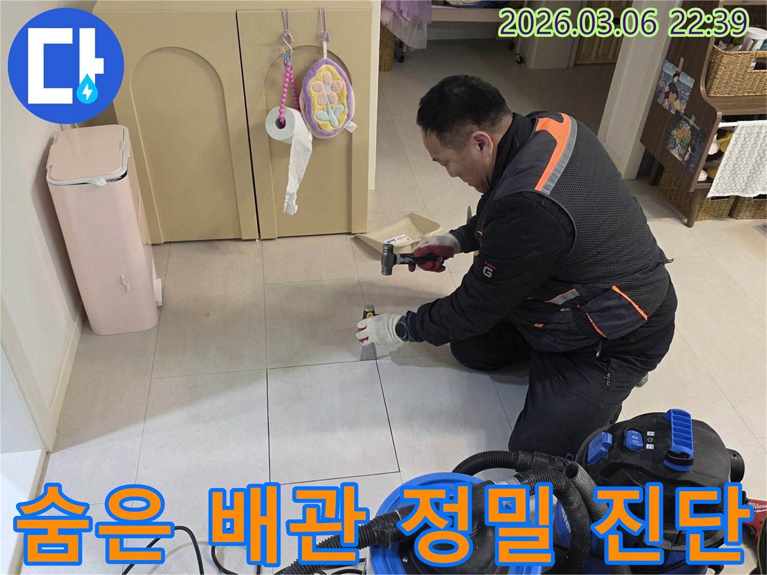 누수 전문가가-바닥 아래 숨겨진 배관을 점검하고자-타일 제거 작업을 진행하고 있습니다.