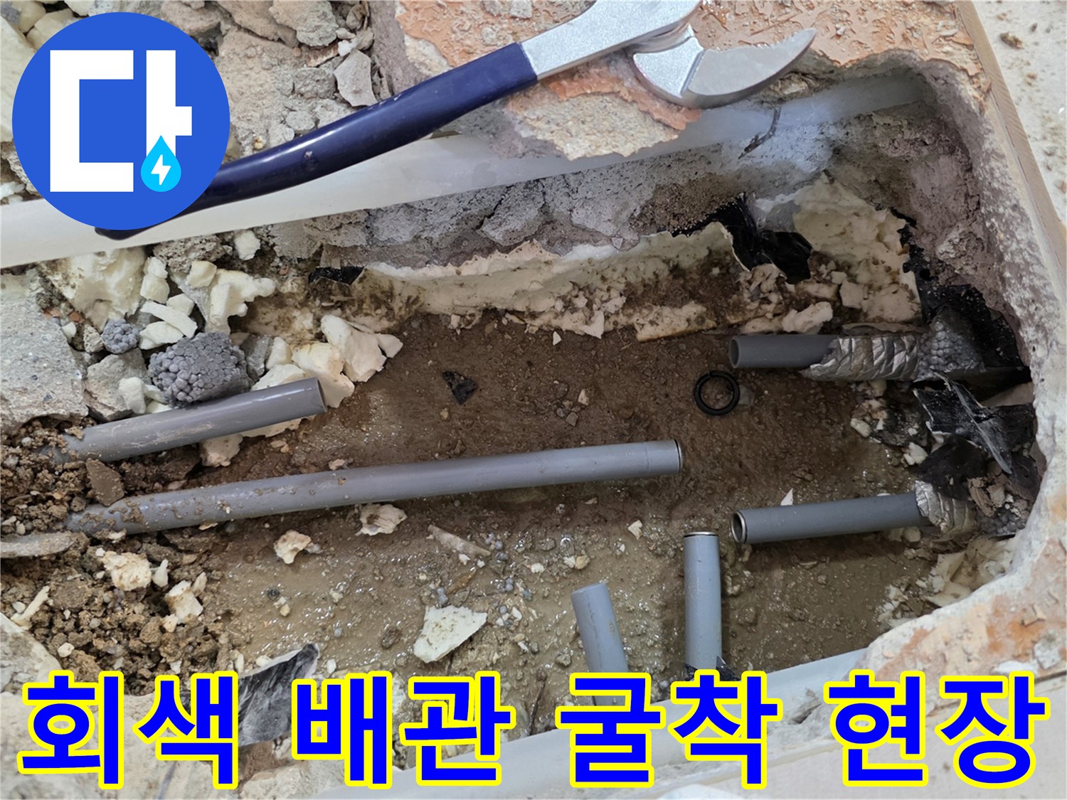바닥 타일 제거 후 노출된 회색 배관과 파손된 연결 부위