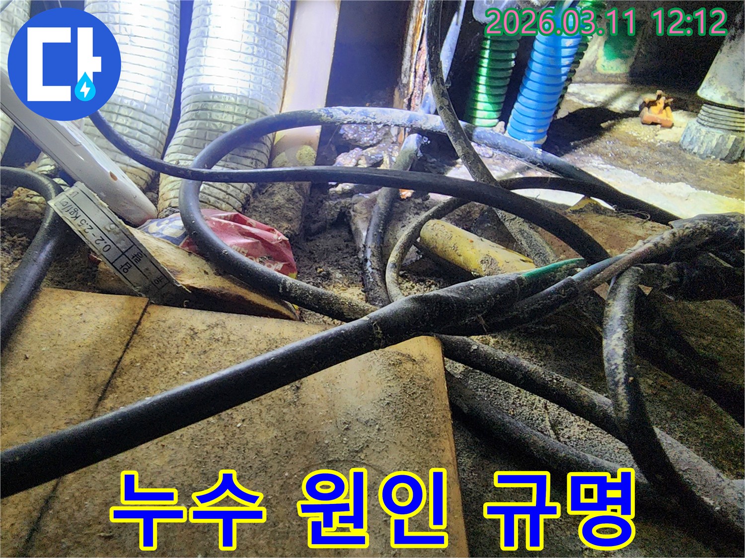 누수-현장에서-복잡하게-얽힌-배관과-전선-사이의-오염된-환경에서-누수-원인을-규명하는-모습을-담은-사진입니다.