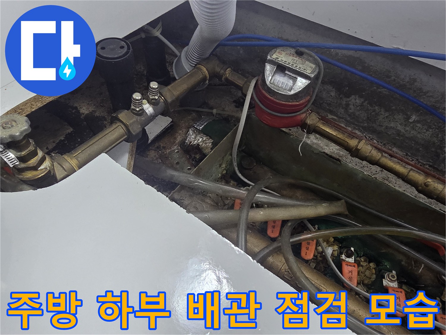 싱크대 아래쪽-금속 배관과 계량기 및 연결된 유연한 호스들