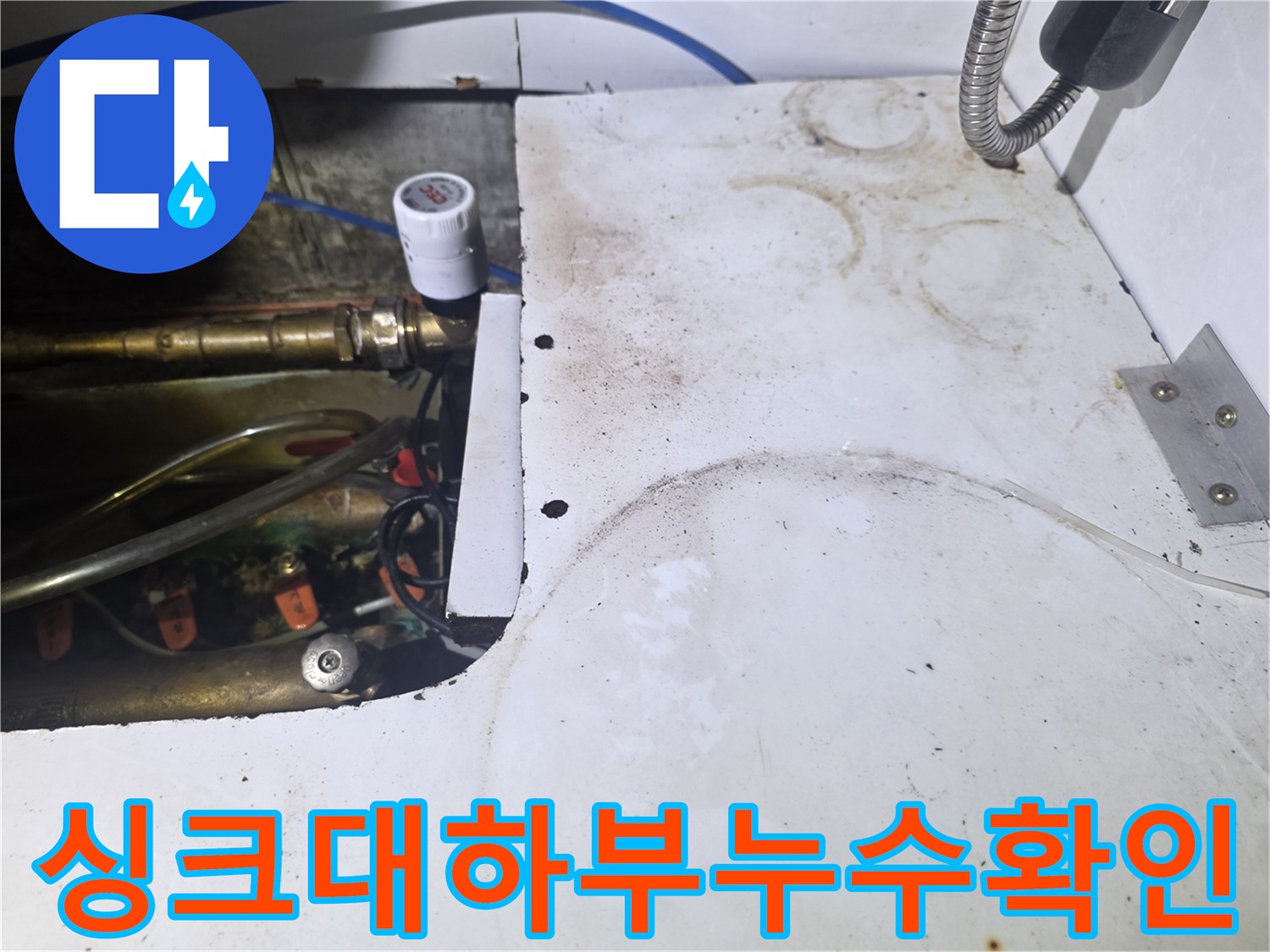 싱크대 하부장 내부의 금속 배관 및 밸브 연결 구조