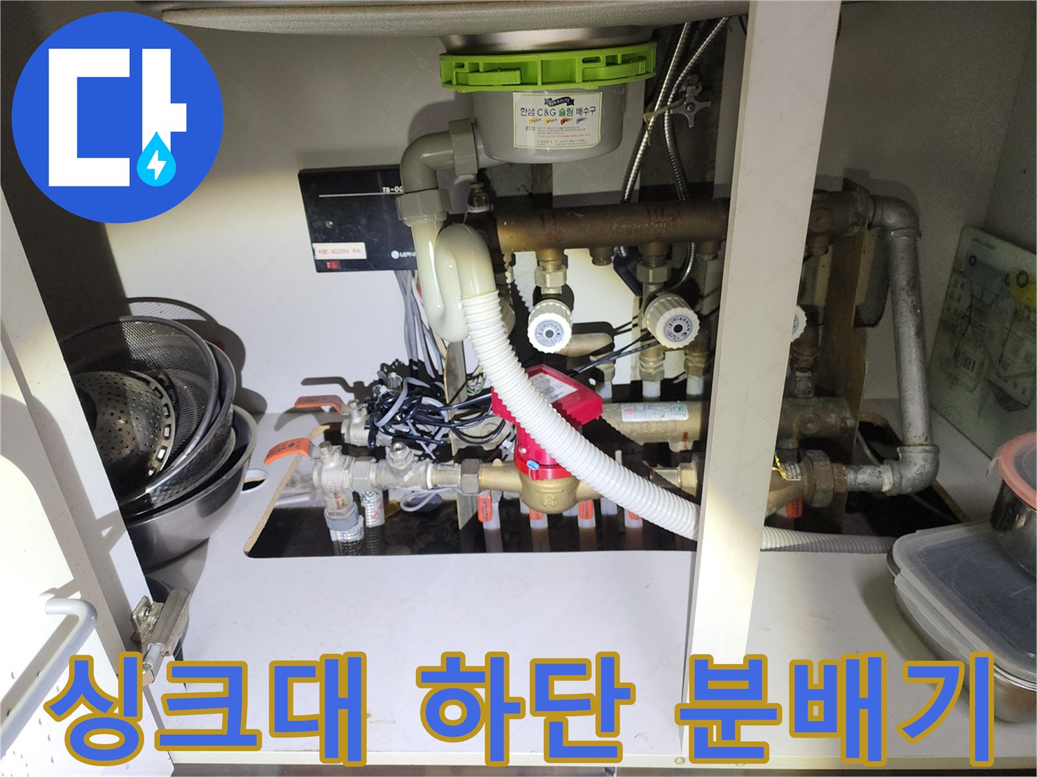용산구 싱크대 하단에 위치한 복잡한 난방 분배기와 배관 연결 상태 사진