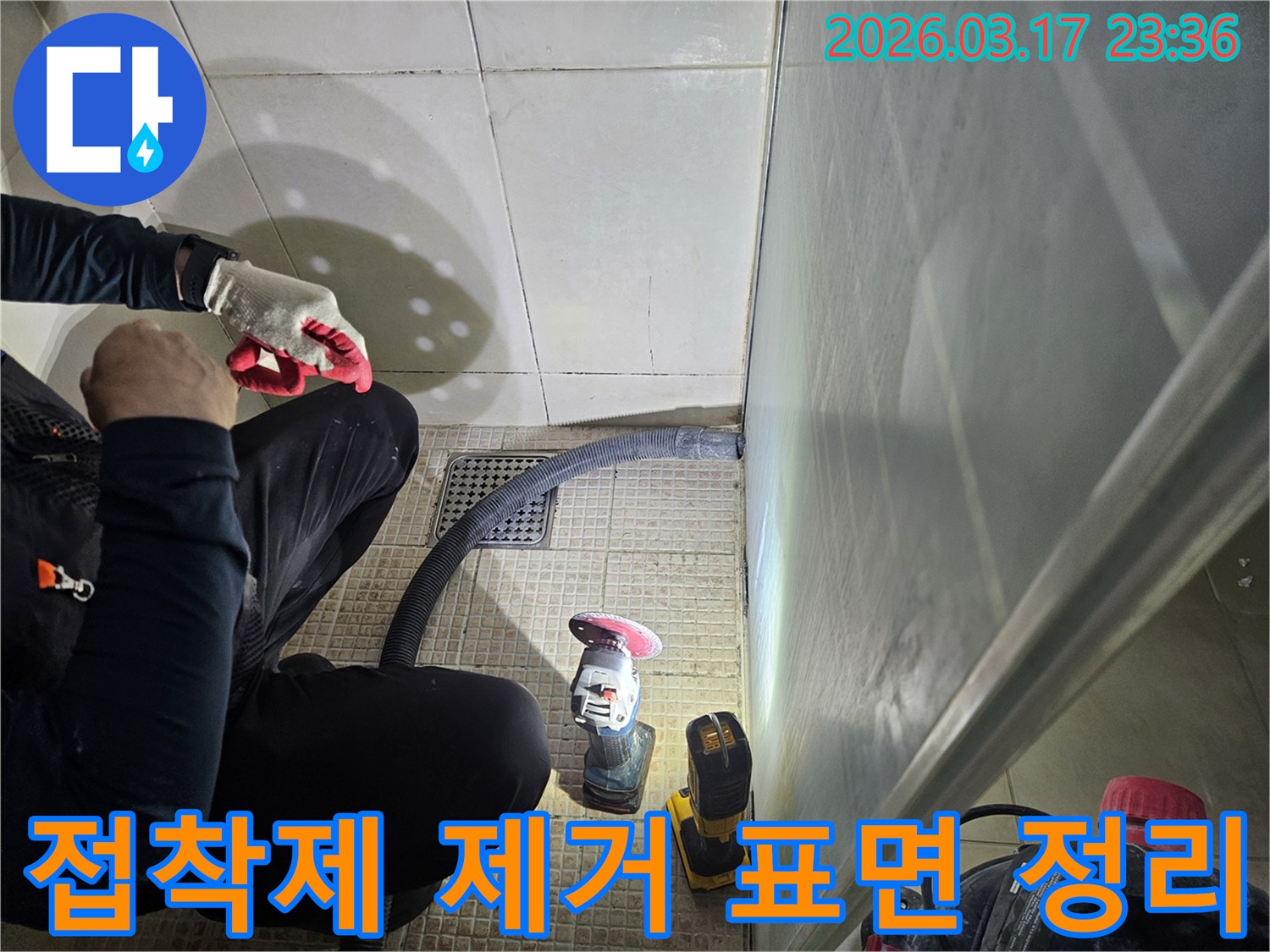 누수 엔지니어가-욕실 바닥의-기존 접착제를 제거하며-표면을 정리하고 있습니다