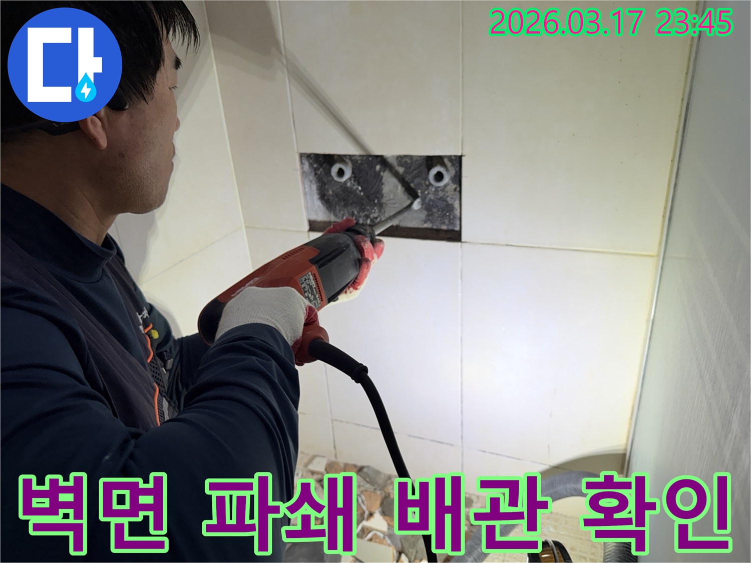 숙련된 기술자가 누수 지점을 찾아내기 위해-벽면 타일을 깨고 내부 배관을 드러내는 작업을 진행하고 있습니다.