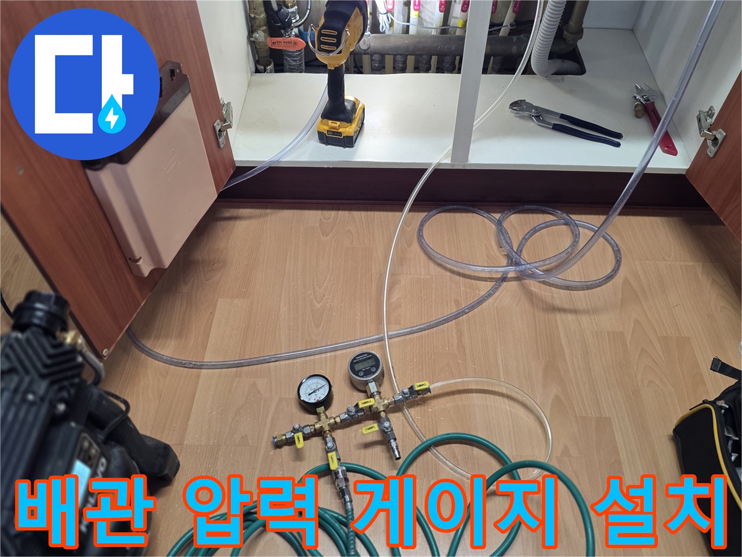 싱크대 하부장 내부-공압 테스트를 위해 연결된 호스와 압력 게이지