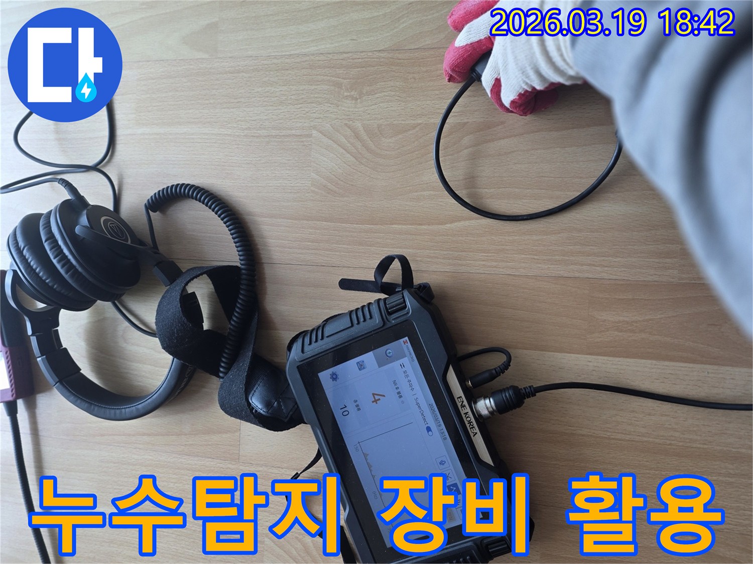 전문가가-누수 탐지 장비와 헤드폰을 사용하여-바닥에서 발생하는-미세한 누수 소리를-집중적으로 듣고 분석하는 장면입니다