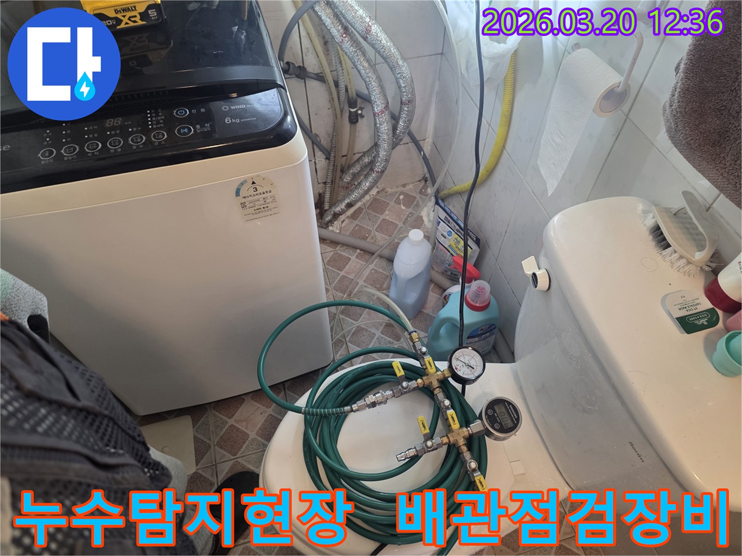 누수 엔지니어가 화장실에서 세탁기 옆 배관과 변기 주변을-정밀 누수 탐지 장비로 검사하며-누수 원인을 파악하고 있습니다