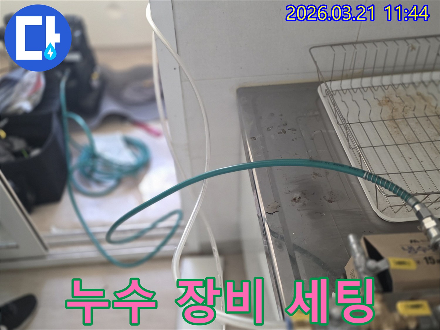 숙련된 누수 엔지니어가-싱크대 하부 배관에-누수탐지 장비를 정성껏 연결하고 있습니다