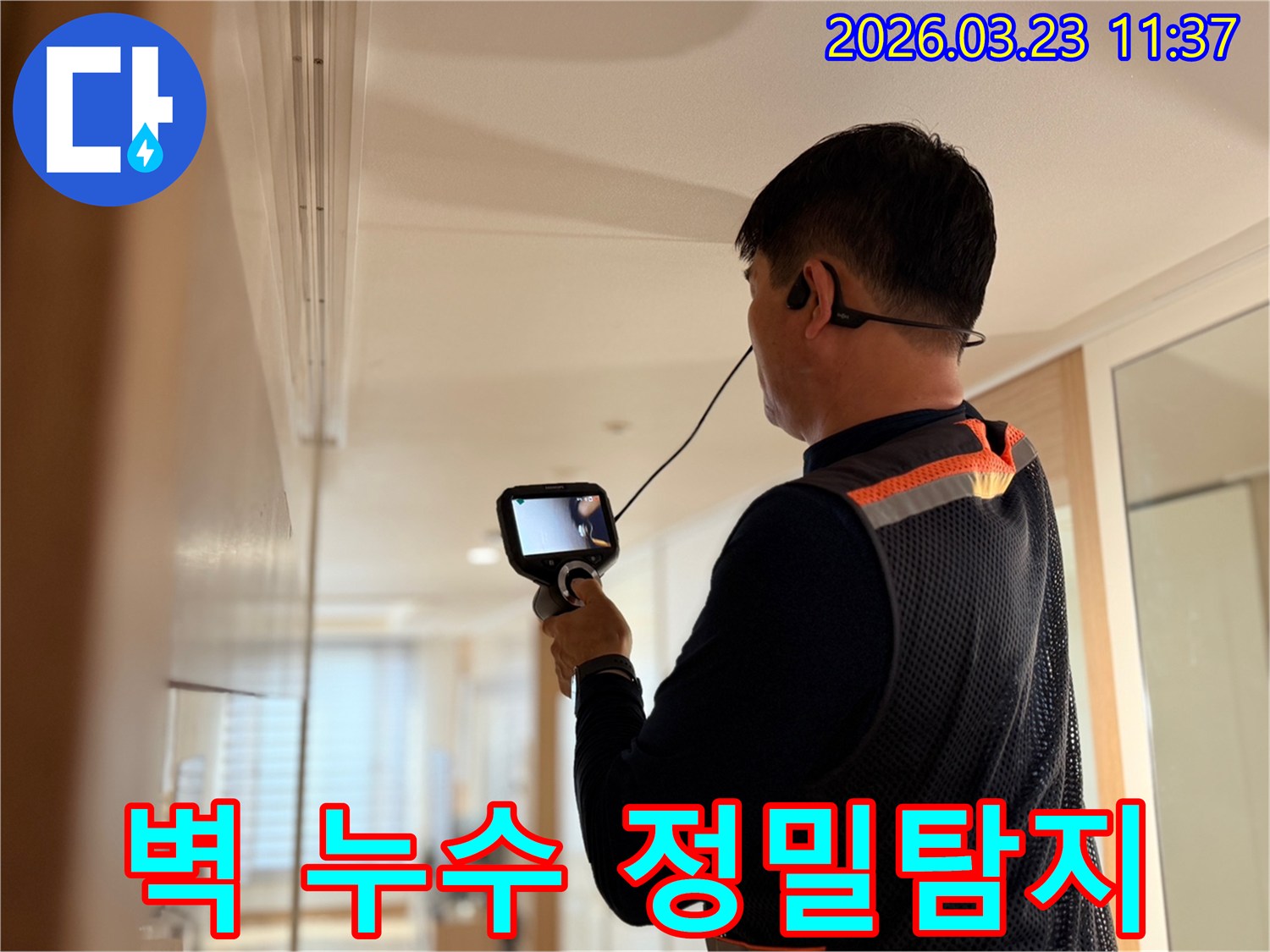 누수 전문가가 벽 내부의 누수 원인을 찾기 위해 고성능 탐지 장비를 사용하여 세밀하게 조사하는 장면
