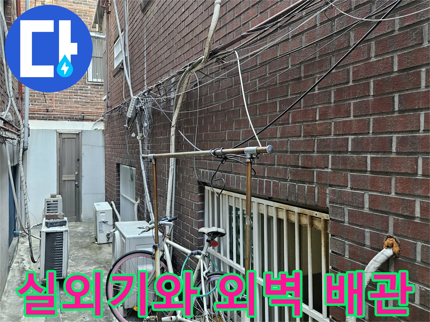 실외기 주변 벽면을 따라 설치된 배관과 자전거가 있는 건물 통로