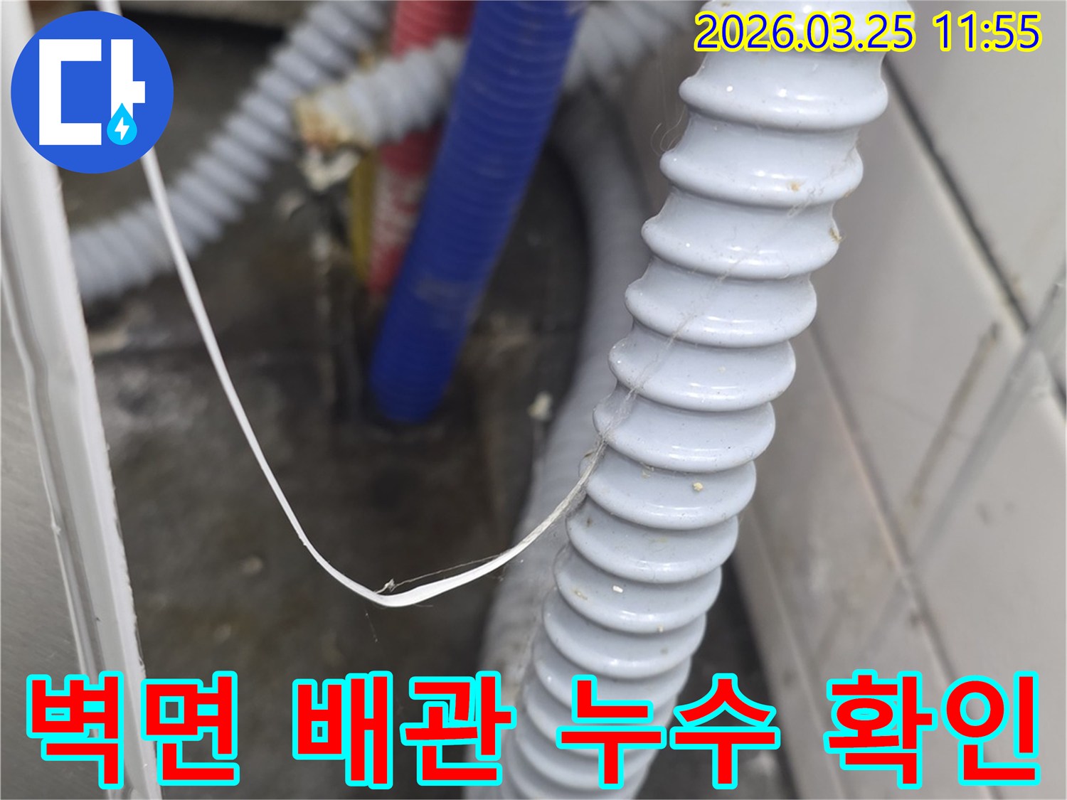 벽면을 따라 설치된-주름진 배수 호스와-빨간색-파란색 수도관 주변에서-누수 흔적을 찾는-면밀한 점검 모습
