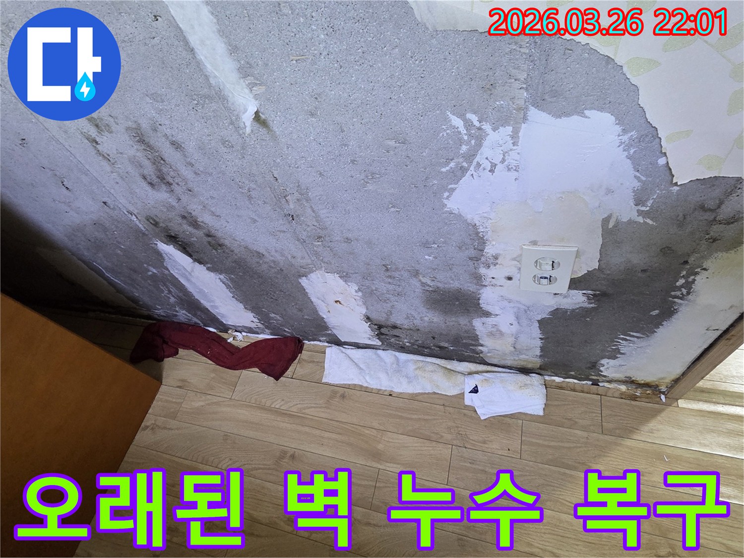 오랜-기간-누수로-인해-벽지가-벗겨지고-심한-얼룩과-곰팡이가-생긴-콘크리트-벽면-아래-물기를-흡수하는-수건이-놓인-현장