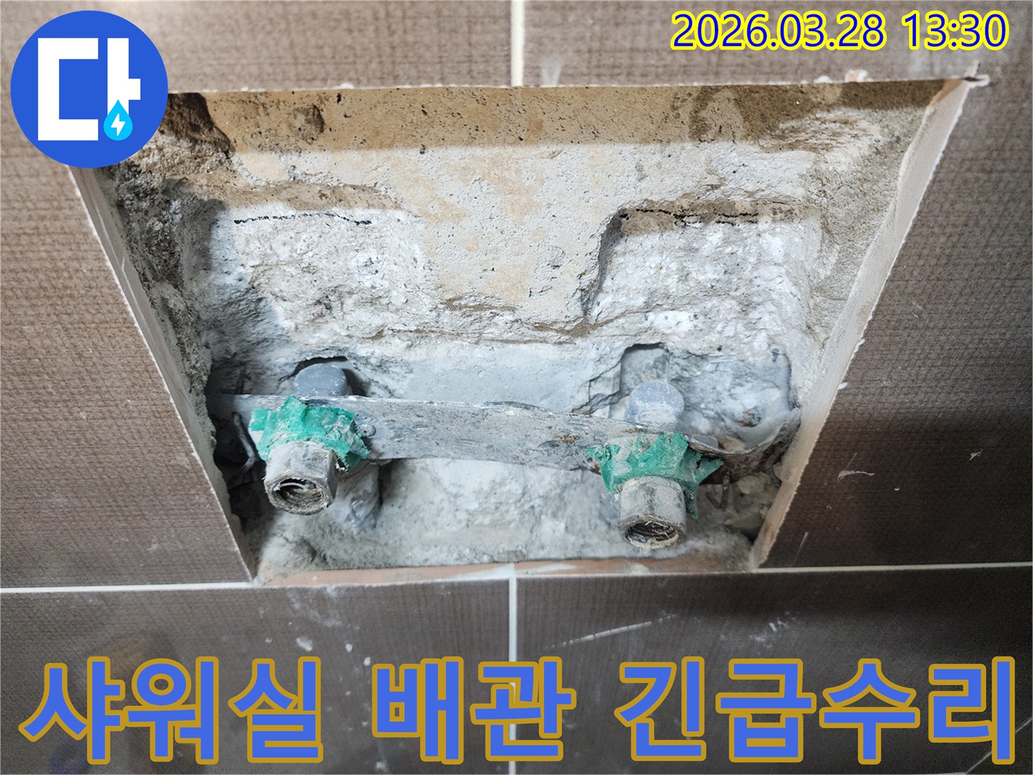 아파트 샤워실 벽면 내부에서 발생한 오래된 배관 부식으로 인한 누수 지점을 긴급하게 수리하기 위해 개방된 현장입니다-신속한 조치가 필요합니다.