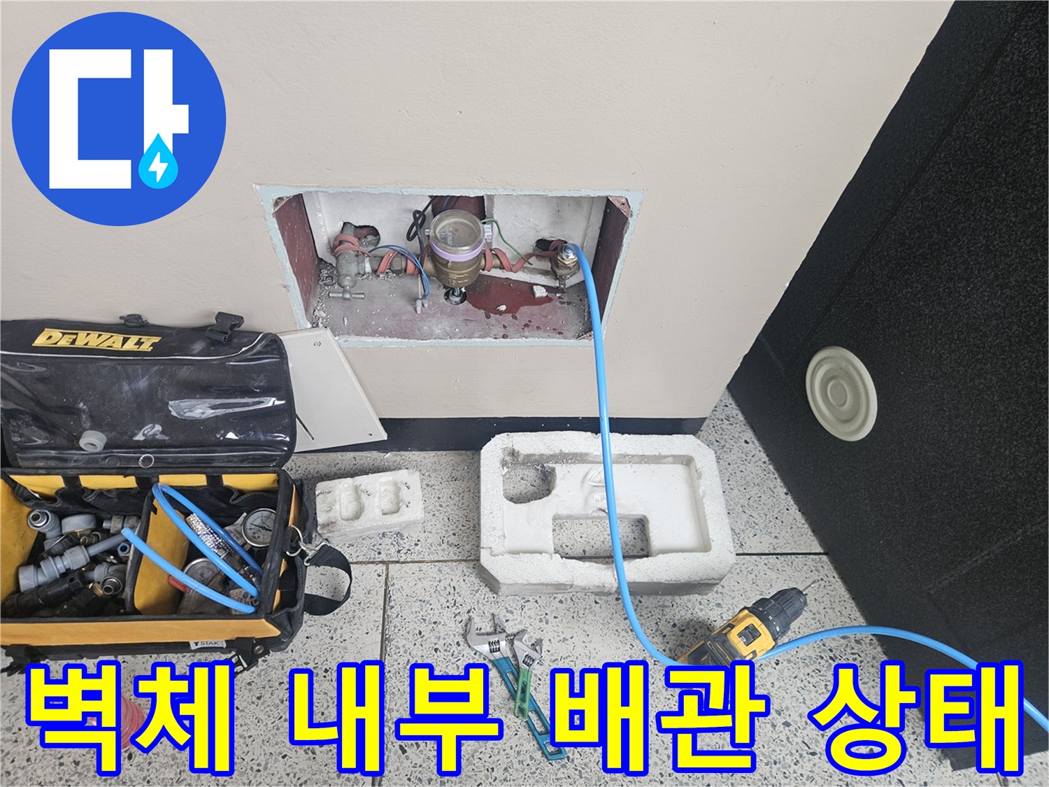 벽면을 절개하여 드러낸 배관 연결 부위와 공구함