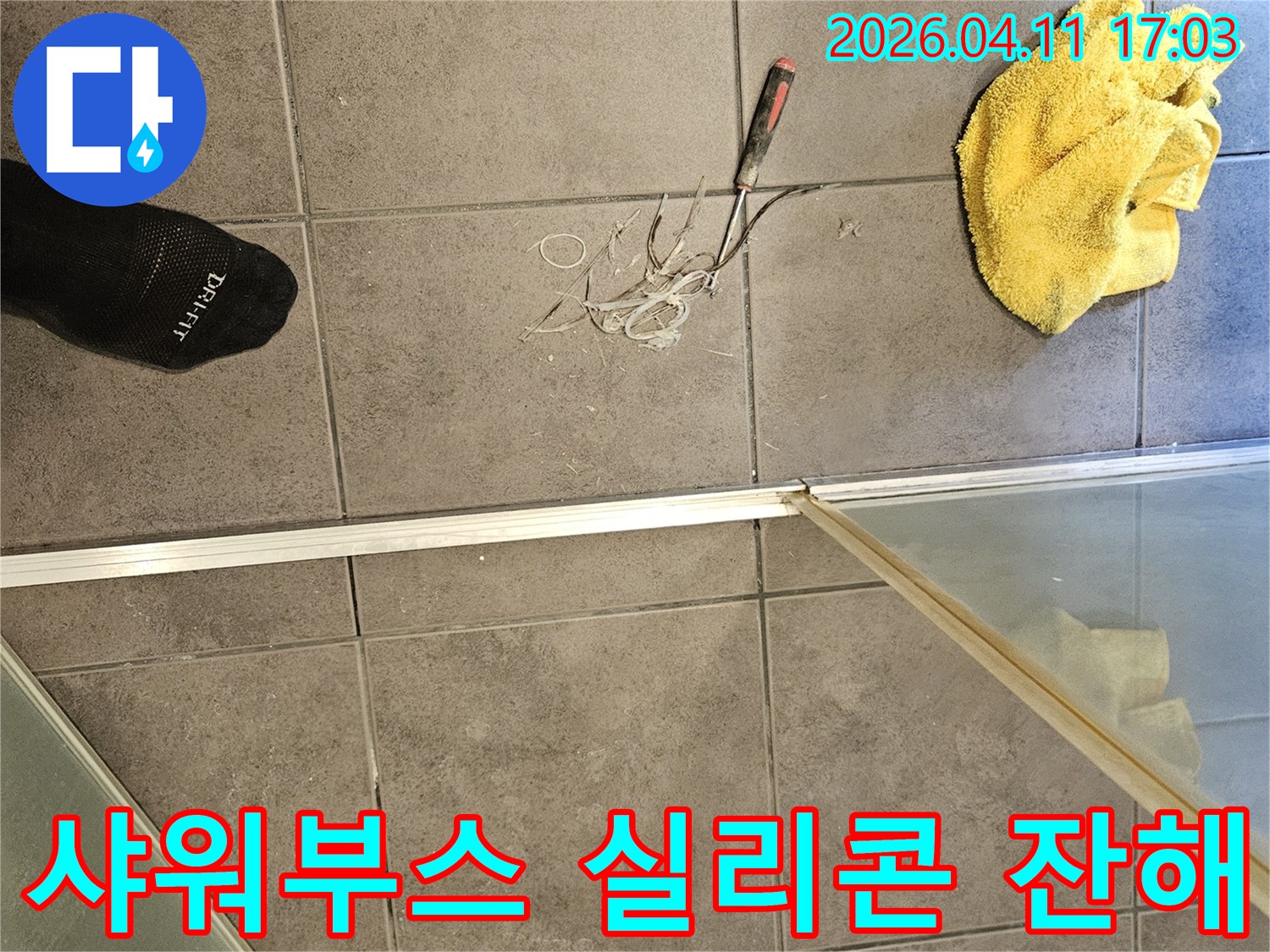 욕실 바닥 타일 위-노란 수건과 공구-그리고 샤워부스에서 제거된 실리콘 잔해물들