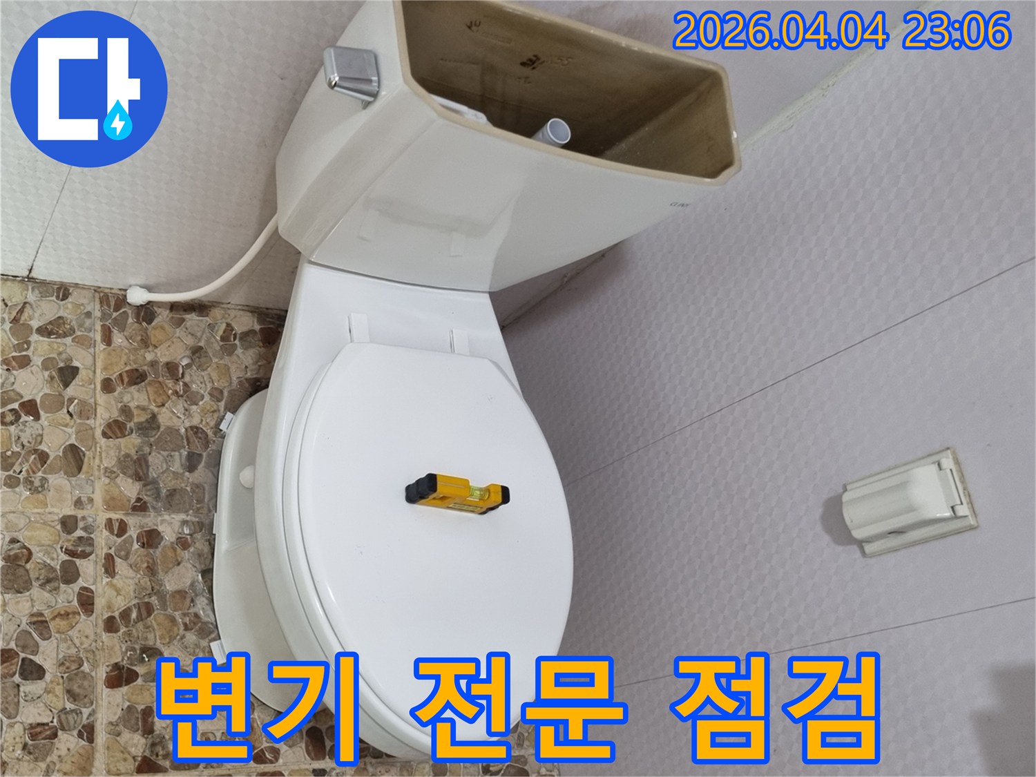 변기 물탱크가 열려 내부 부품이 노출된 상태로-수평계가 변기 시트 위에 놓여-전문적인 누수 점검이 진행 중입니다