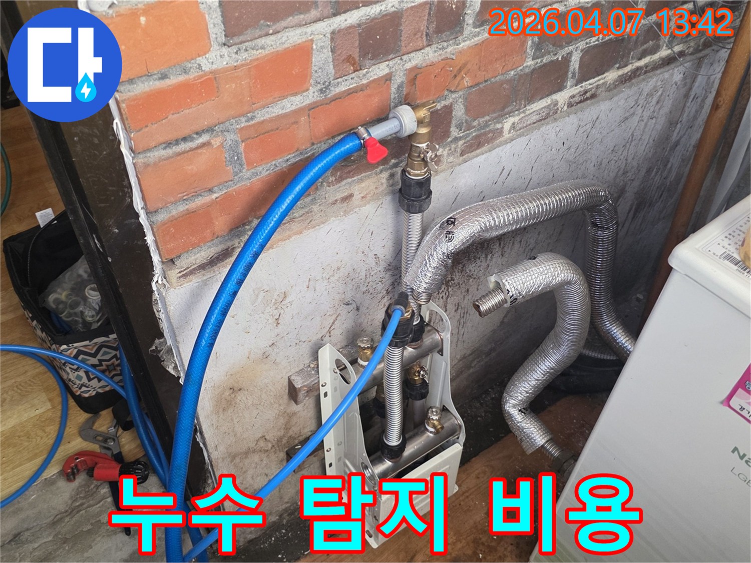 벽돌 벽 옆에-누수 탐지 장비가-설치되어 있으며-파란색 호스가-배관에 연결되어-정밀 진단을 준비 중입니다.