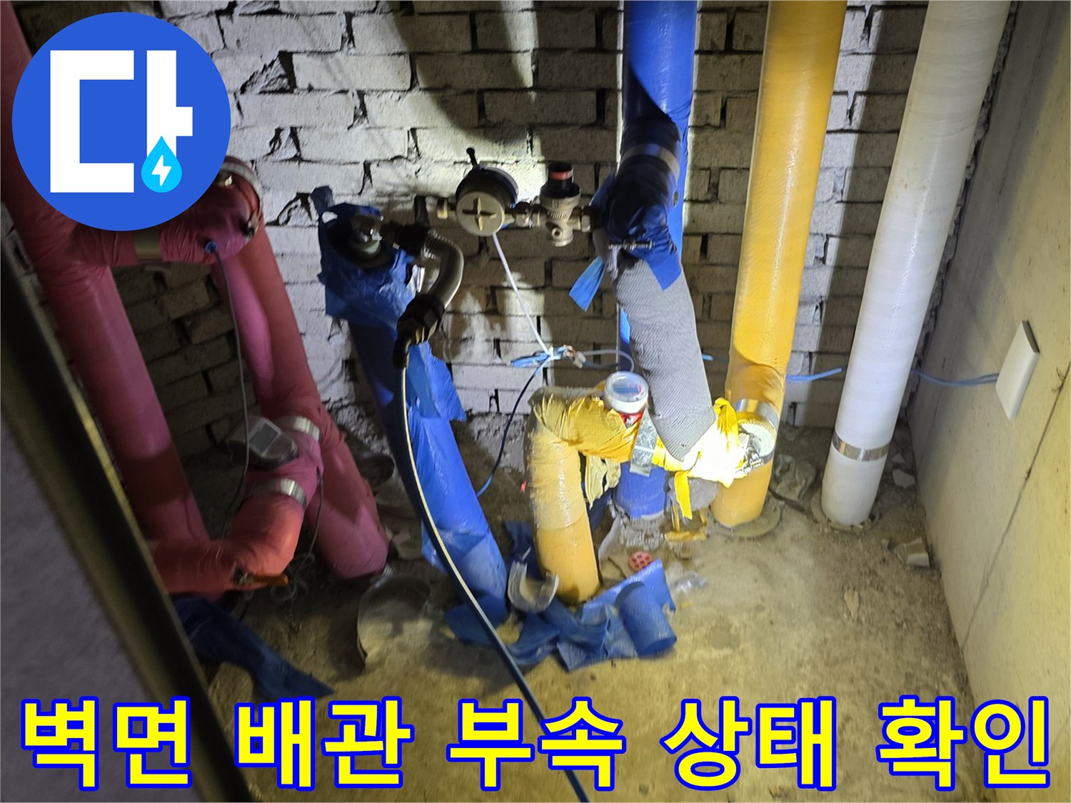 분홍색과 파란색 배관이 교차하는 지점의 누수 여부를 점검하는 사진