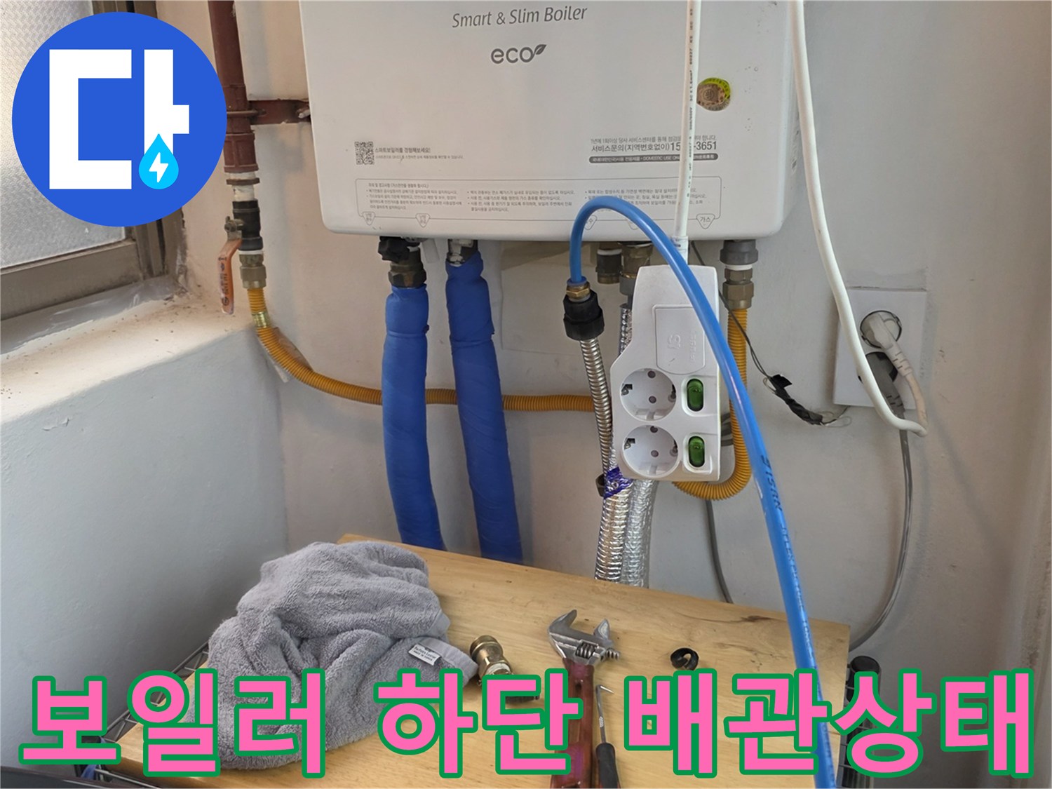 보일현 하단에 연결된 파란색 온수 배관과 전기 콘센트 모습