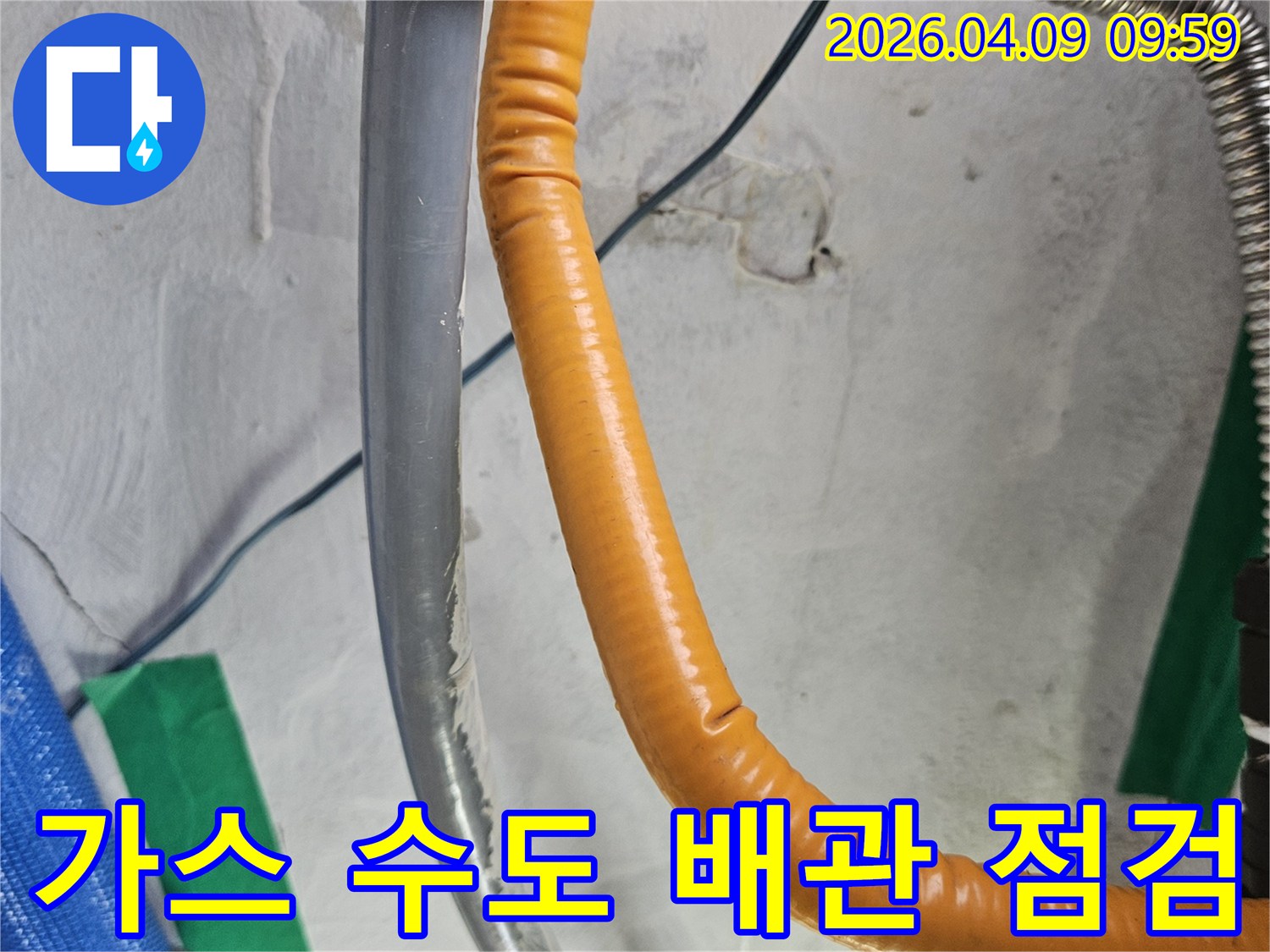 벽을 따라 설치된 주황색 가스배관과 회색 수도배관-두 배관의 연결 부위와 주변 상태를 점검하는 모습