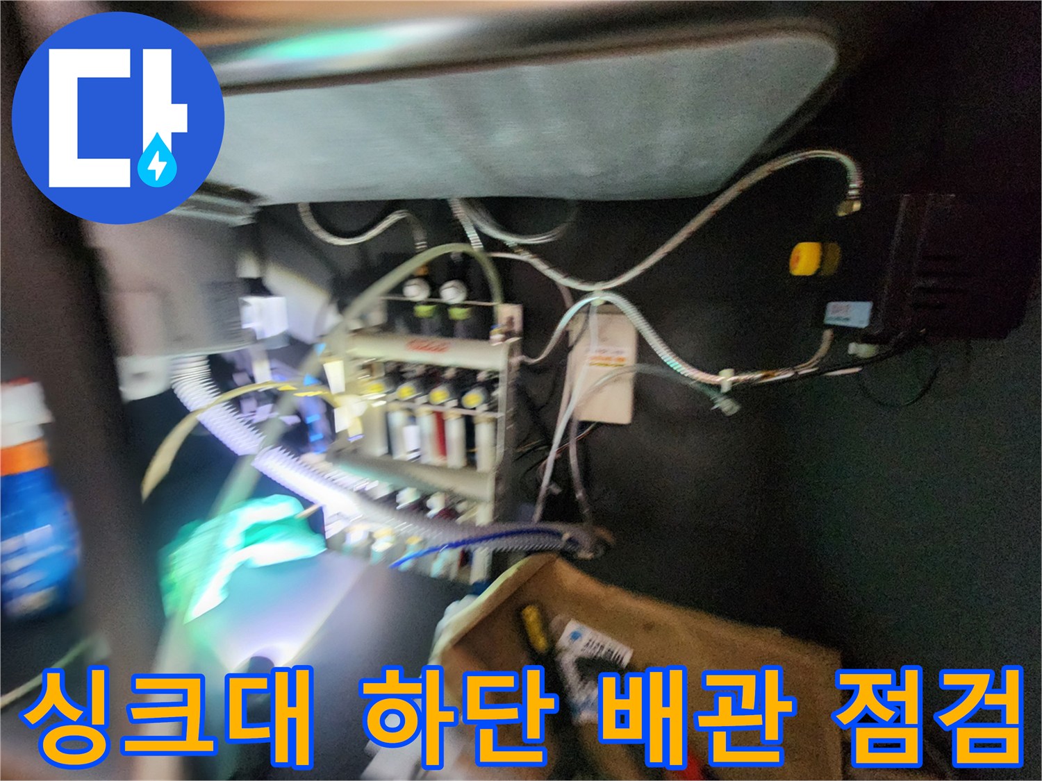 싱크대 하부장 내부의 복잡한 배관과 가스 탐지 장비 연결 모습