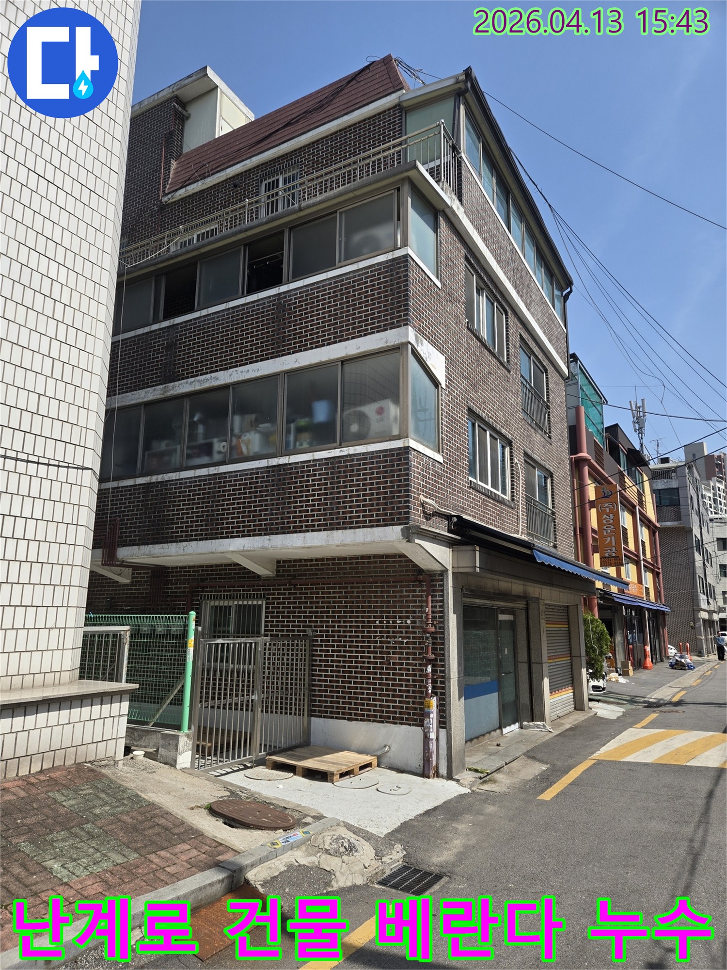 난계로에-위치한-이-건물-외벽은-베란다-확장-공사-이후-발생한-누수-문제를-해결하기-위해-전문가가-현장을-점검하는-모습을-보여줍니다.