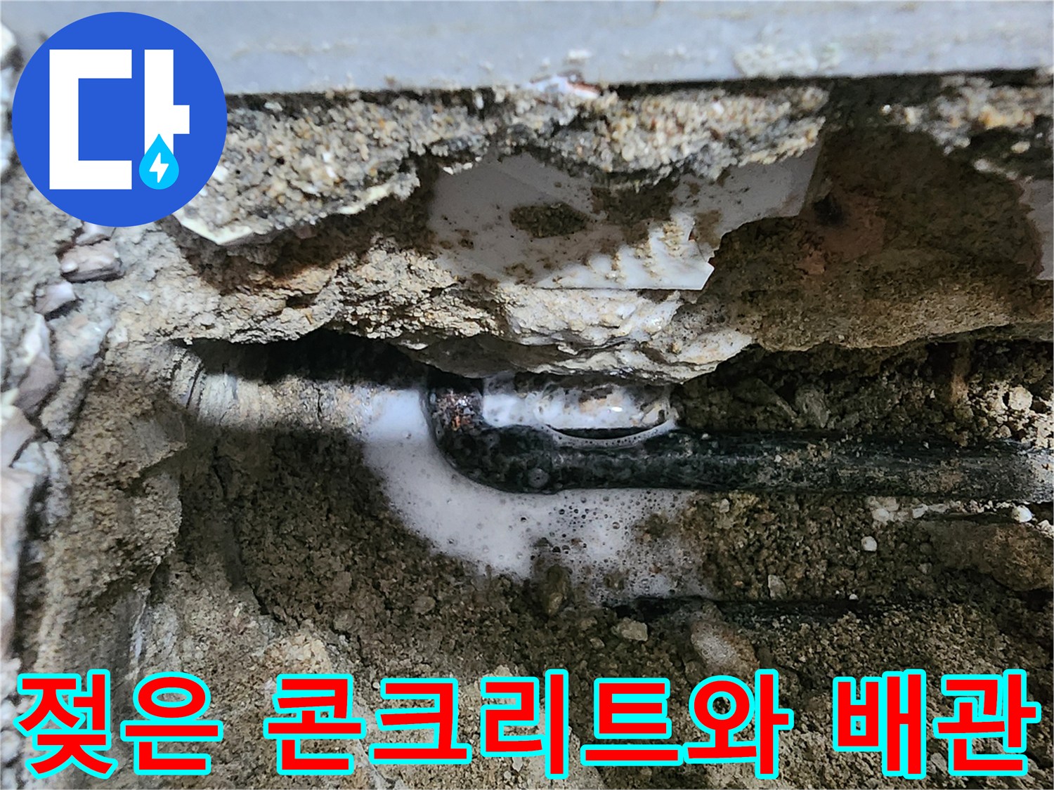 매립된 배관 주위의 습한 토양과 콘크리트 파손 부위를 나타냅니다.