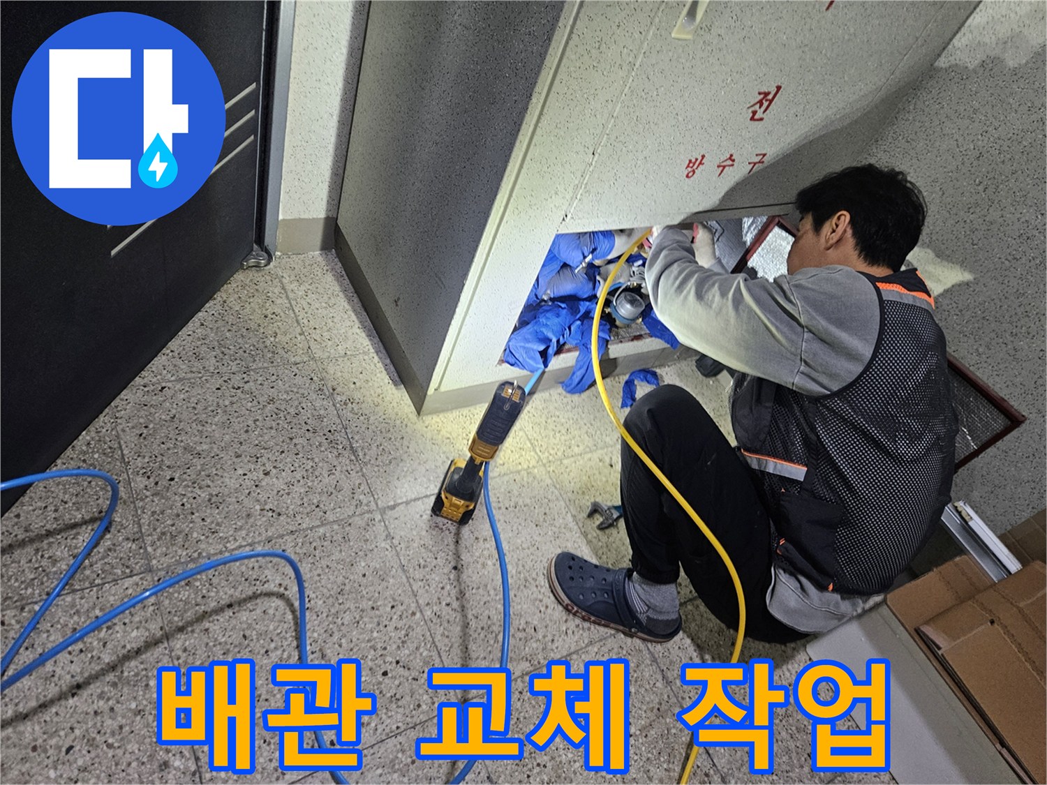 싱크대 밑 좁은 공간에서 배관 보수를 위해 도구를 사용하는 모습