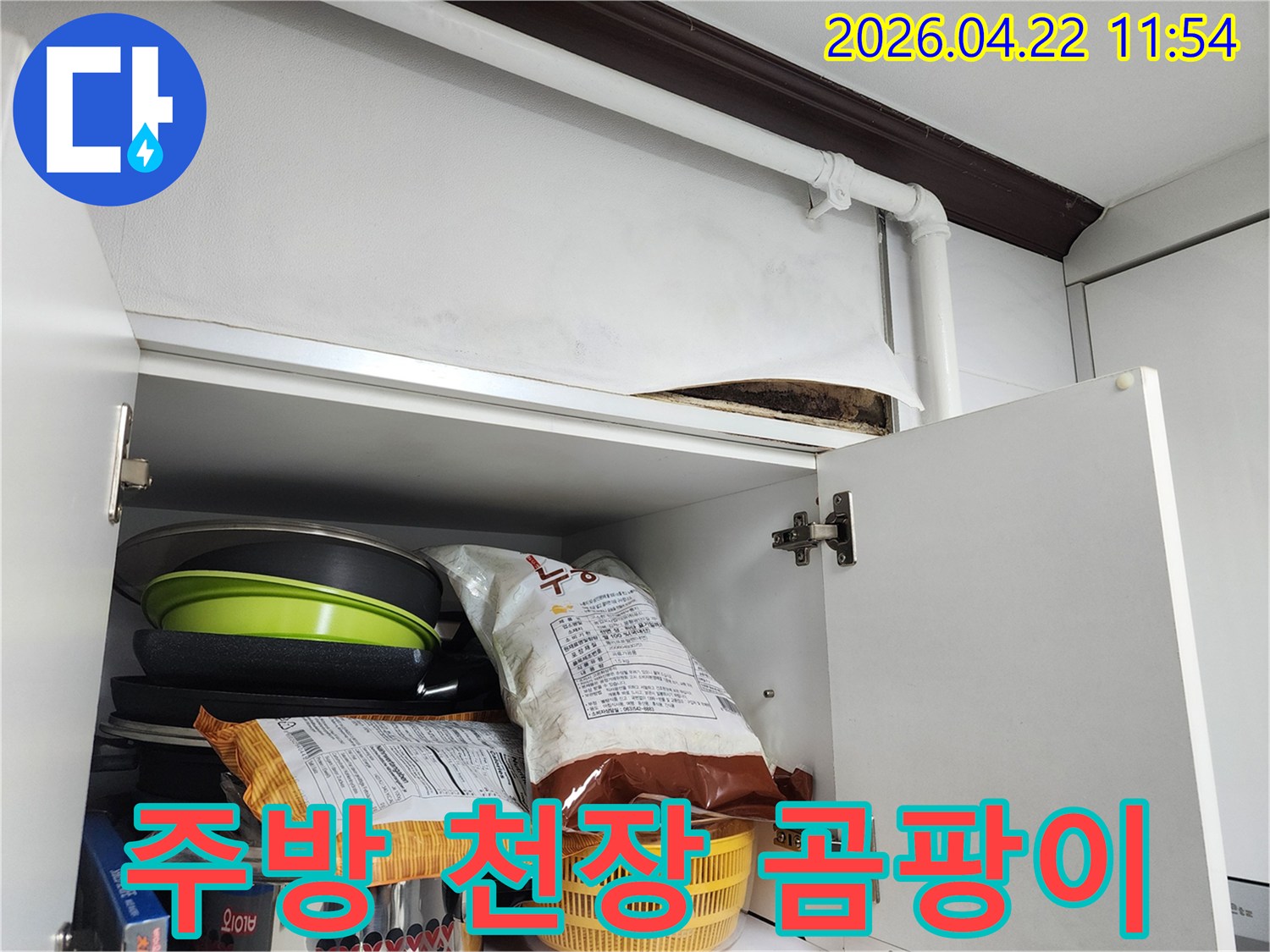 주방 상부장 위 천장에서 물-샘으로 인해 발생한 검은 곰팡이와 마감재 손상을 보여주는 이미지입니다