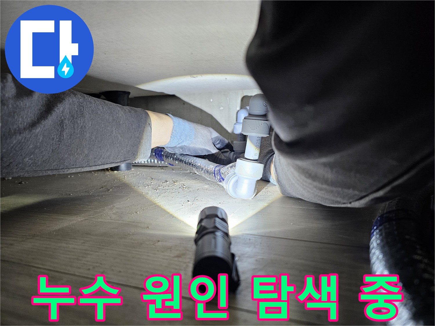 누수-전문가가-손전등을-이용해-어두운-배관-하부를-정밀하게-조사하는-장면