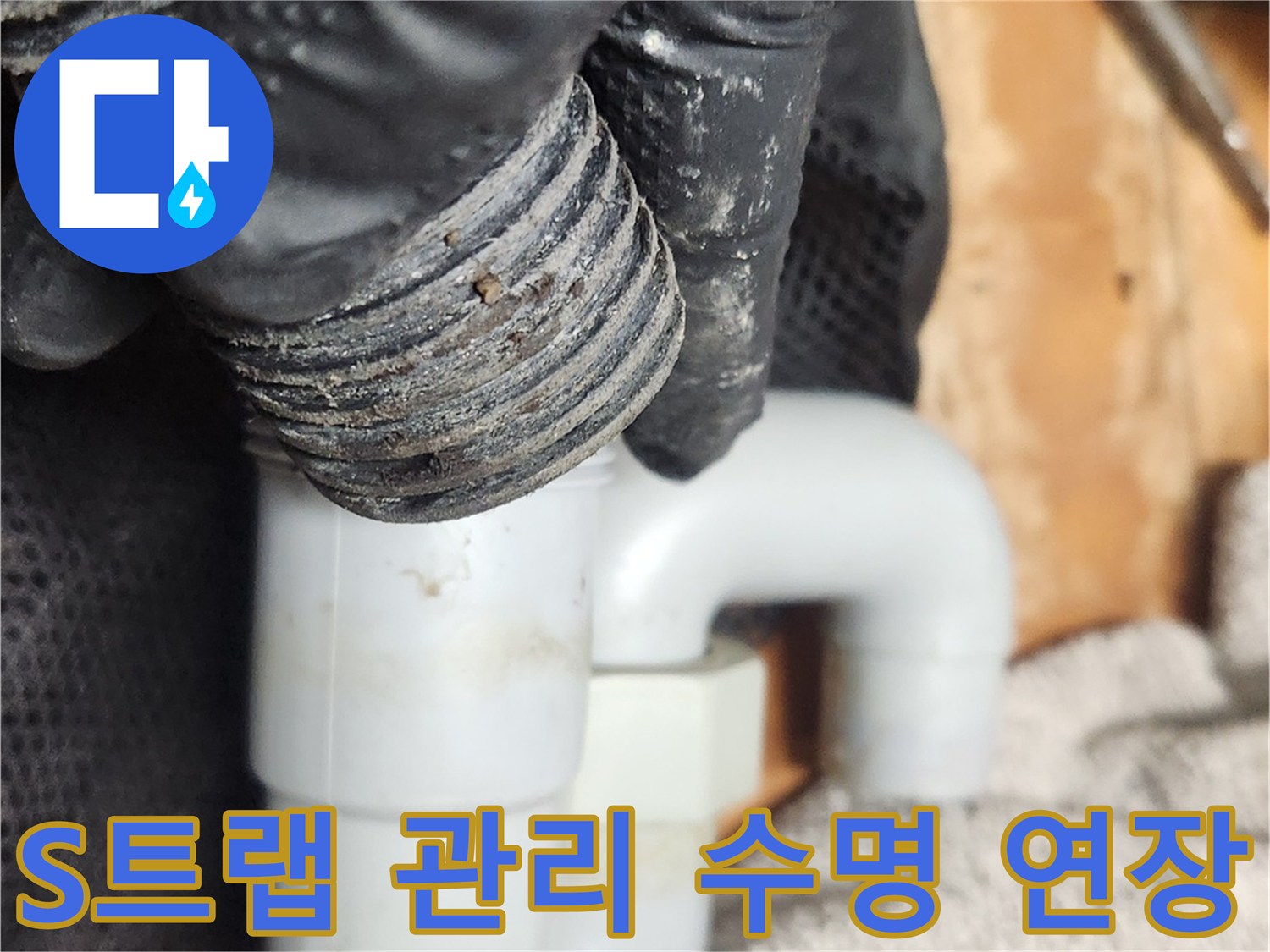 작업자가 검은 장갑을 끼고-S트랩 배관을 분리하여-배관 수명 연장을 위한 클리닝을 진행하고 있습니다