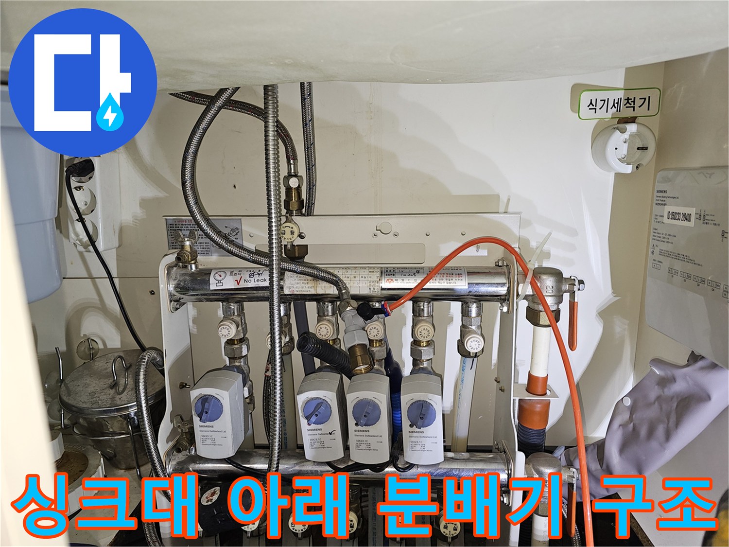 복잡하게 연결된 싱크대 하부장 내부의 난방 및 온수 분배기 상세 모습